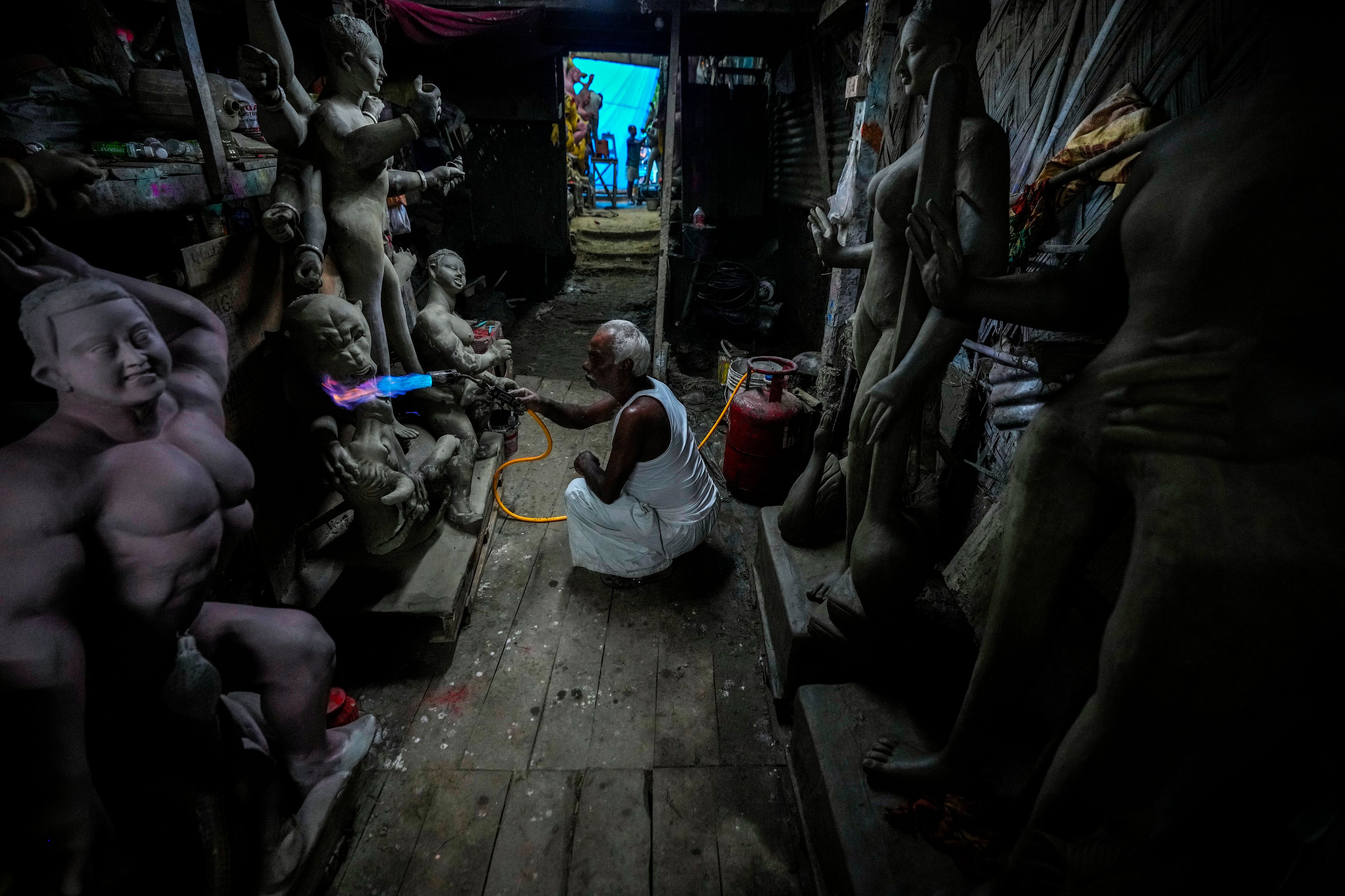 Ratan Paul, 70, uses a blowtorch to dry a mud idol of the Hindu goddess Durga at his workshop during the Durga Puja festival in Guwahati, India, Friday, Oct. 4, 2024. (AP Photo/Anupam Nath)