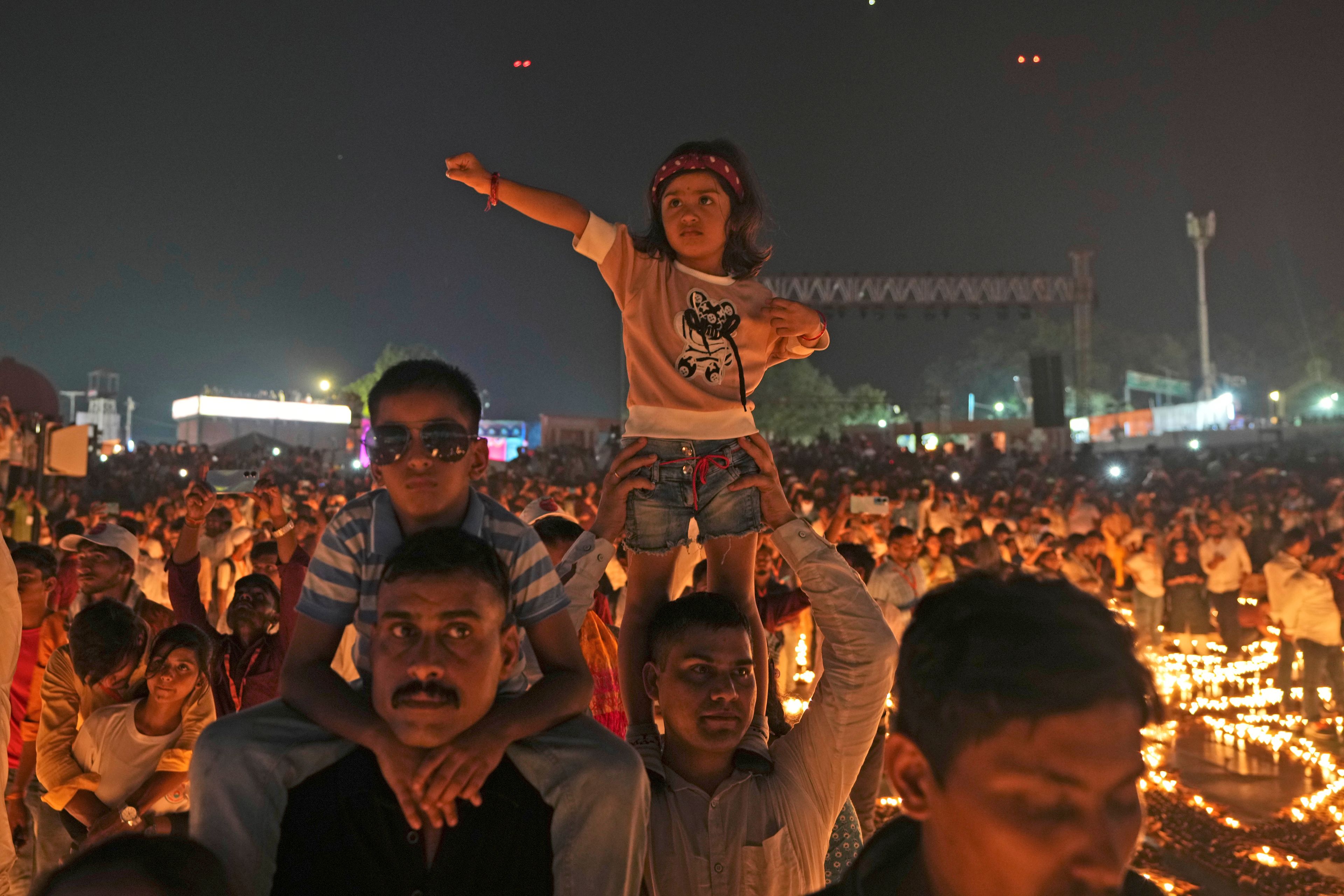 People stand in between rows of lit earthen lamps on the banks of the Saryu river during Deepotsav celebrations, an event organized by the Uttar Pradesh state government on the eve of Diwali, in Ayodhya, India, Wednesday, Oct. 30, 2024. (AP Photo/Rajesh Kumar Singh)