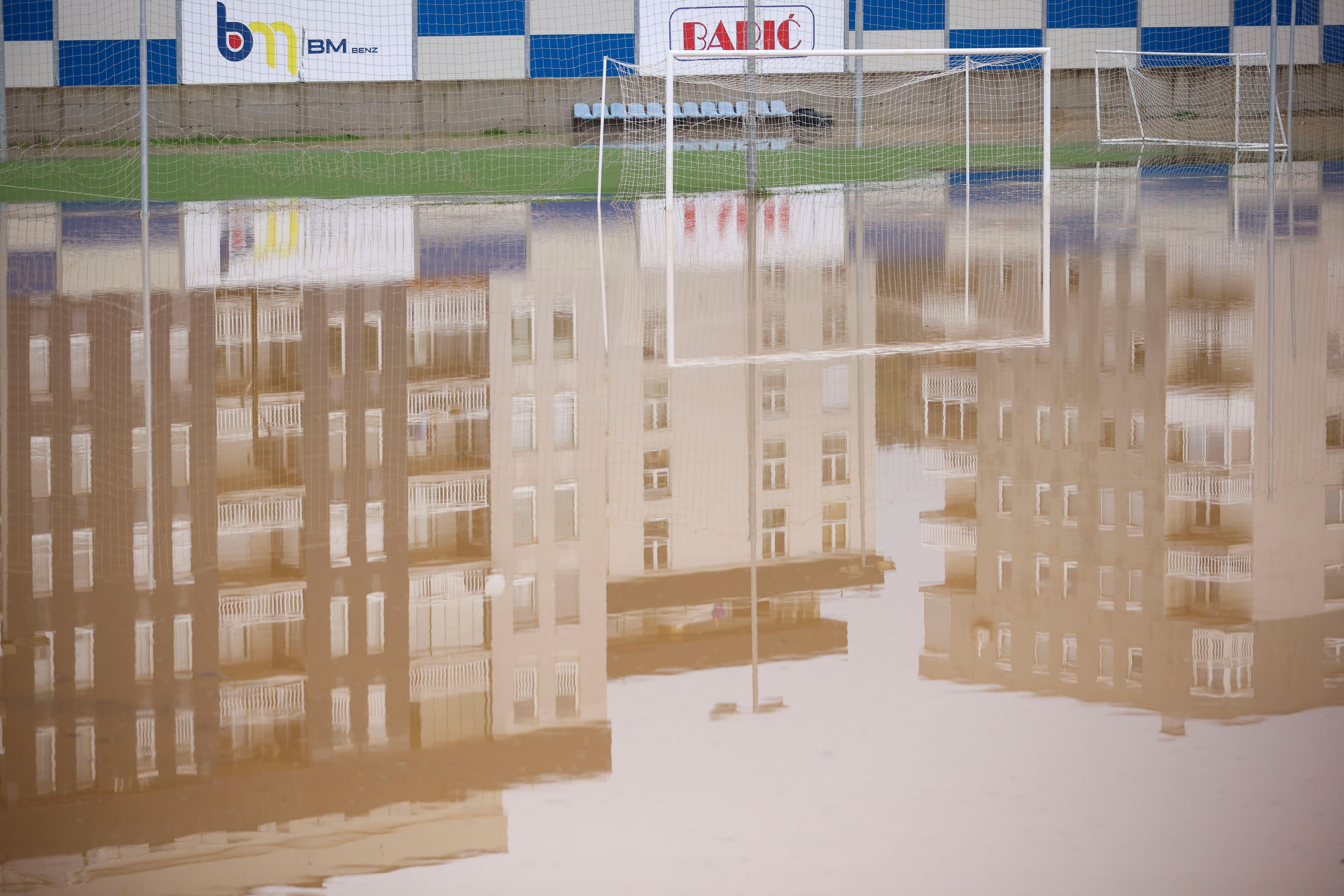 Apartment buildings are reflected at a flooded soccer field after a heavy rain in the village of Kiseljak, northern Bosnia, Friday, Oct. 4, 2024. (AP Photo/Armin Durgut)