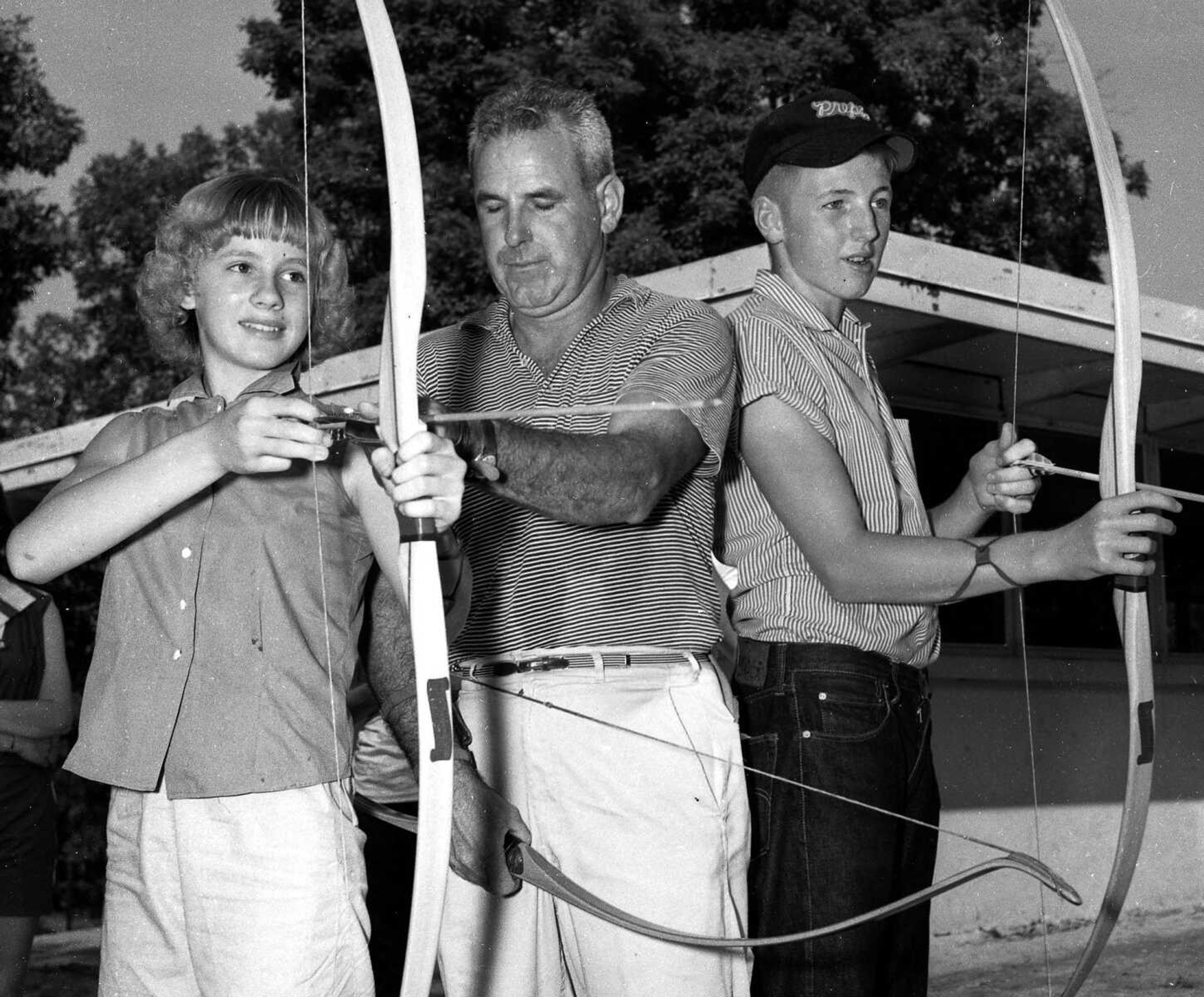 Al Hoskin, field service agent for the Conservation Commission, instructed Judy Schabbing and John Lohmeier on how to handle a bow and arrow at Club Camp on Lake Wappapello in the summer of 1958.