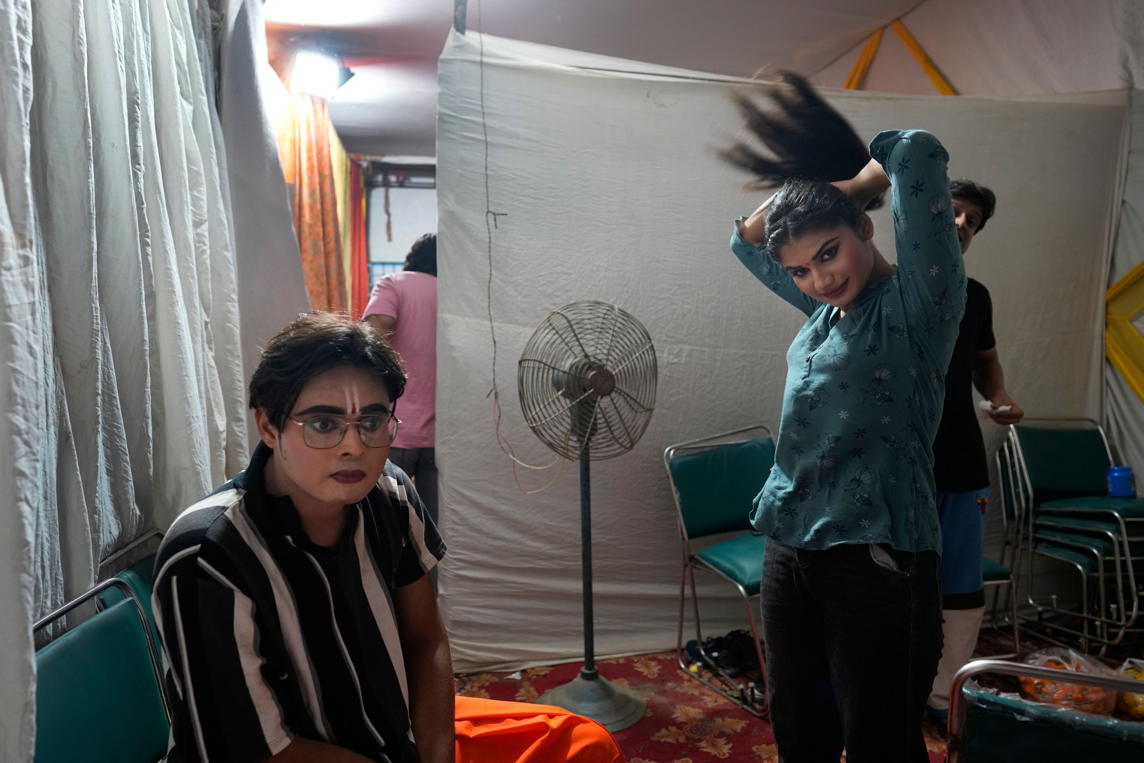 Ashutosh Agnihotri, 23, playing the character of Hindu god Rama, left, rests backstage as Hitanshi Jha, 21, playing the character of Sita, ties her hair at the end of the third day of Ramleela, a dramatic folk re-enactment of the life of Rama according to the ancient Hindu epic Ramayana, in New Delhi, India, Wednesday, Oct. 9, 2024. (AP Photo/Manish Swarup)