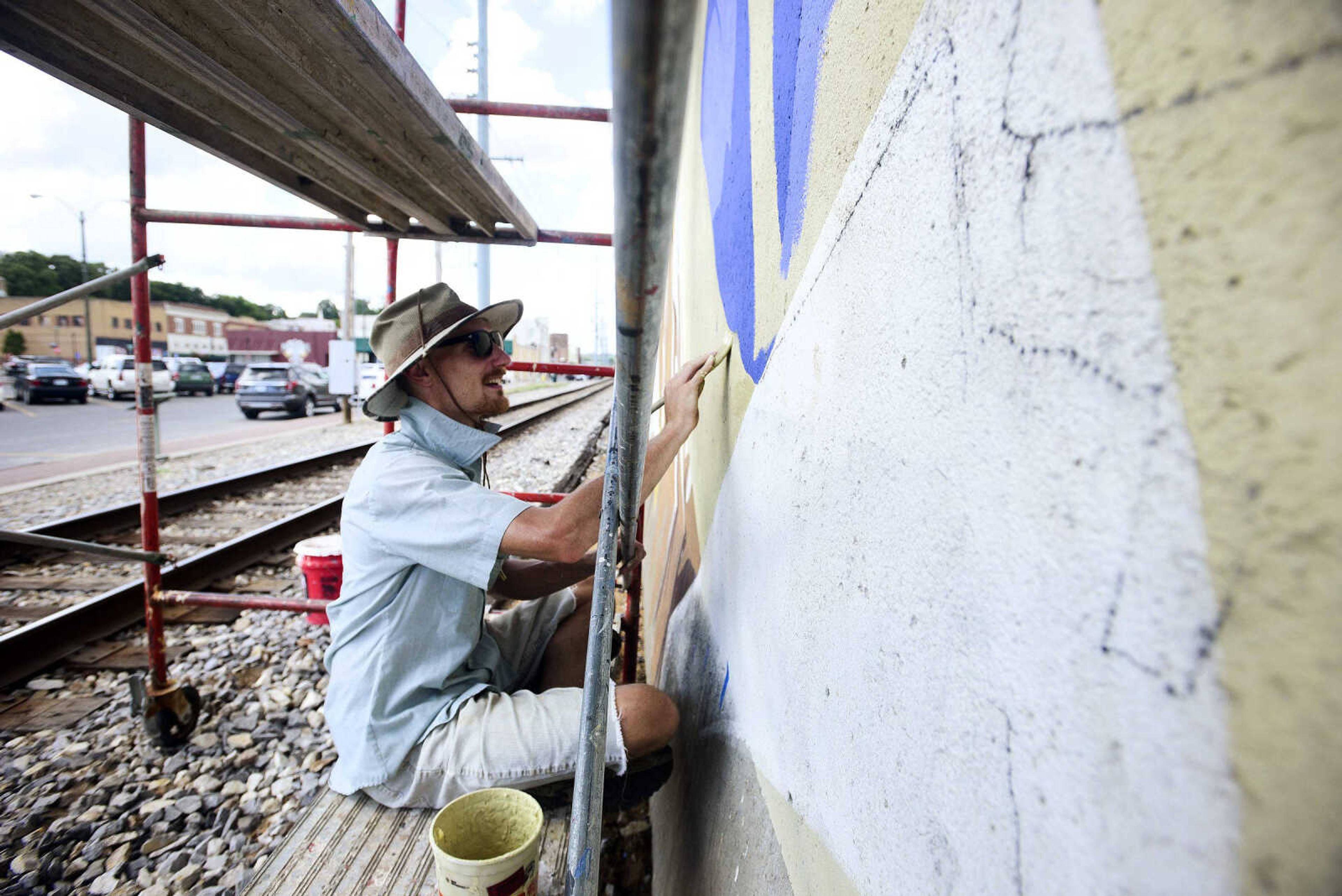 Jess Wells helps paint a mural of the late Gen. Seth McKee on Thursday.