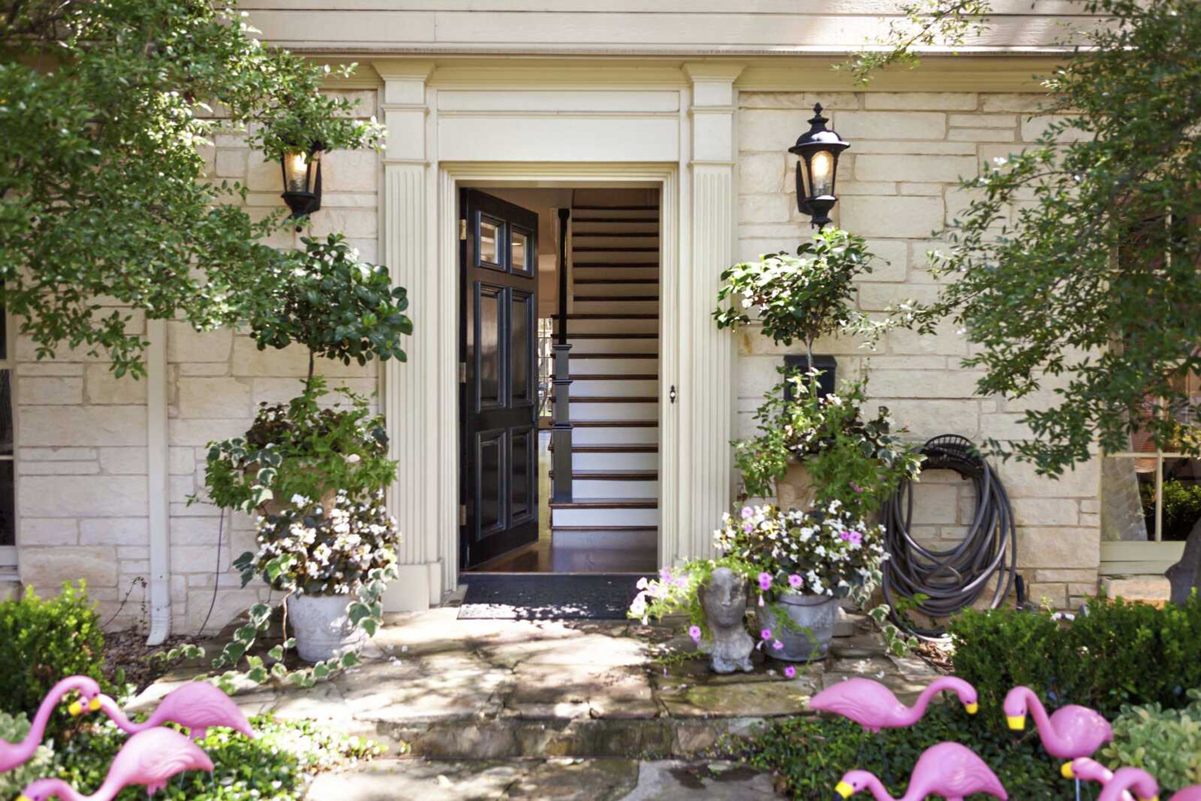 This undated photo provided by Abbe Fenimore shows the delicate leaves and flowers of potted flowering plants which creates a perfect balance with the architectural molding and a dramatic black front door at this entryway designed by Abbe Fenimore of Studio Ten 25 in Dallas, Texas.