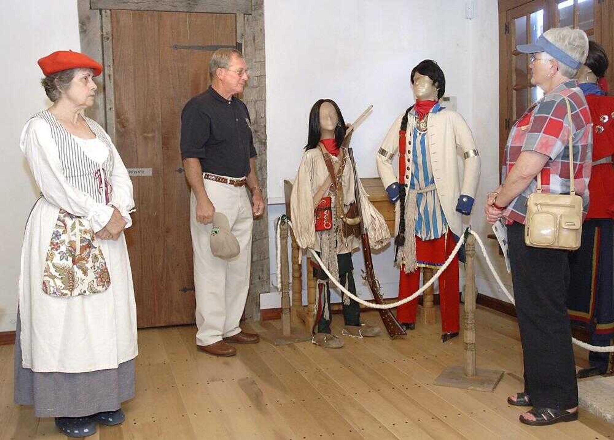 Boots Jessup, left, a docent at the Red House Interpretive Center, presented a bit of local history Sunday to Ronald and Susan Estes of Marble Hill, Mo., next to a display of Cape Girardeau founder Louis Lorimier. The tour was part of the Rediscover Your Cape weekend. (Fred Lynch)