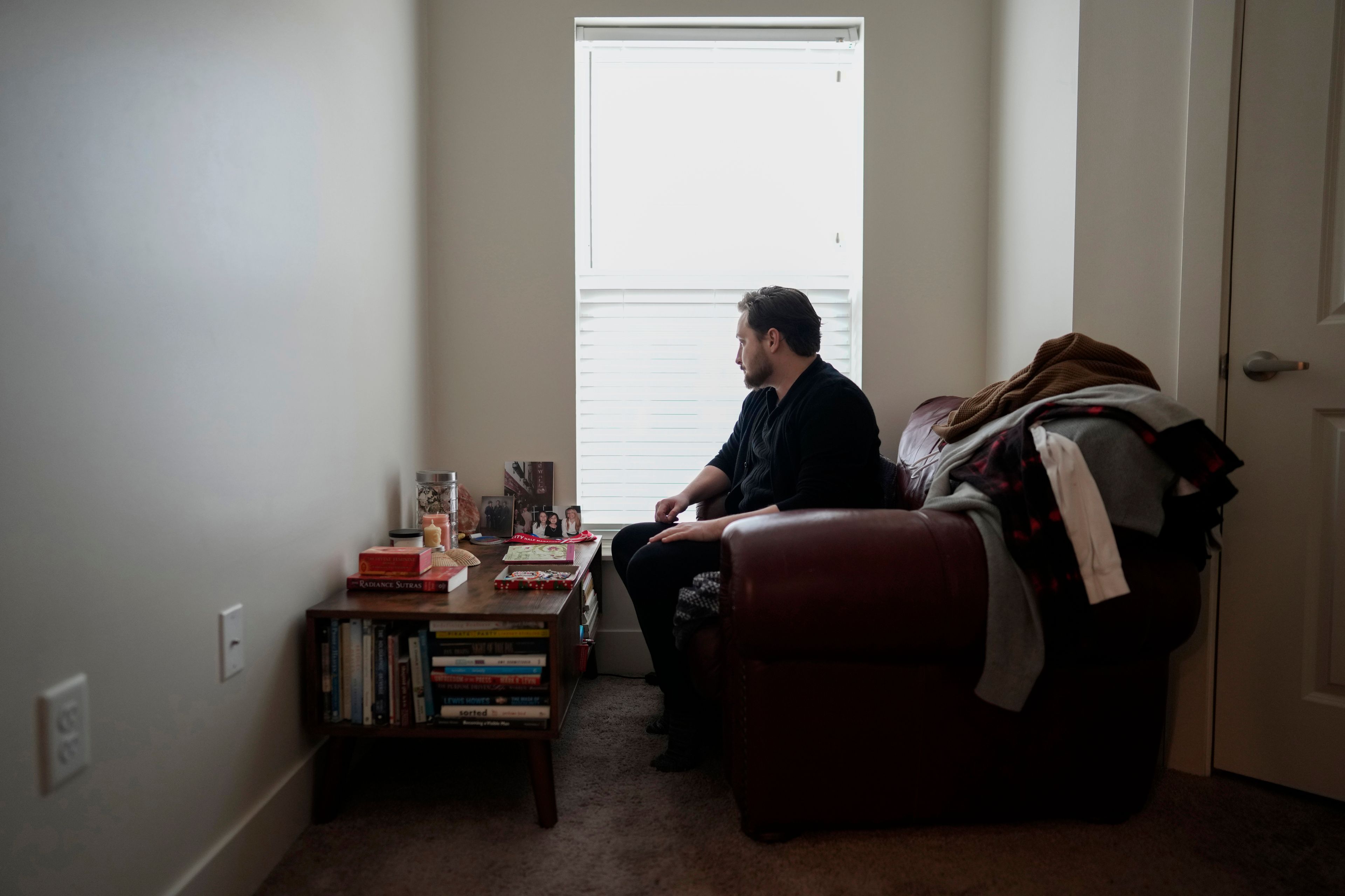 FILE - Ashton Colby looks out the window of his meditation corner in his apartment in Columbus, Ohio, on Thursday, Jan. 18, 2024. Ohio Gov. Mike DeWine announced proposals in January that transgender advocates say could block access to gender-affirming care provided by independent clinics and general practitioners, leaving thousands of adults scrambling for treatment and facing health risks. Colby, 31, fears the clinic where he gets the testosterone he has taken since age 19 would no longer offer it. (AP Photo/Carolyn Kaster, File)