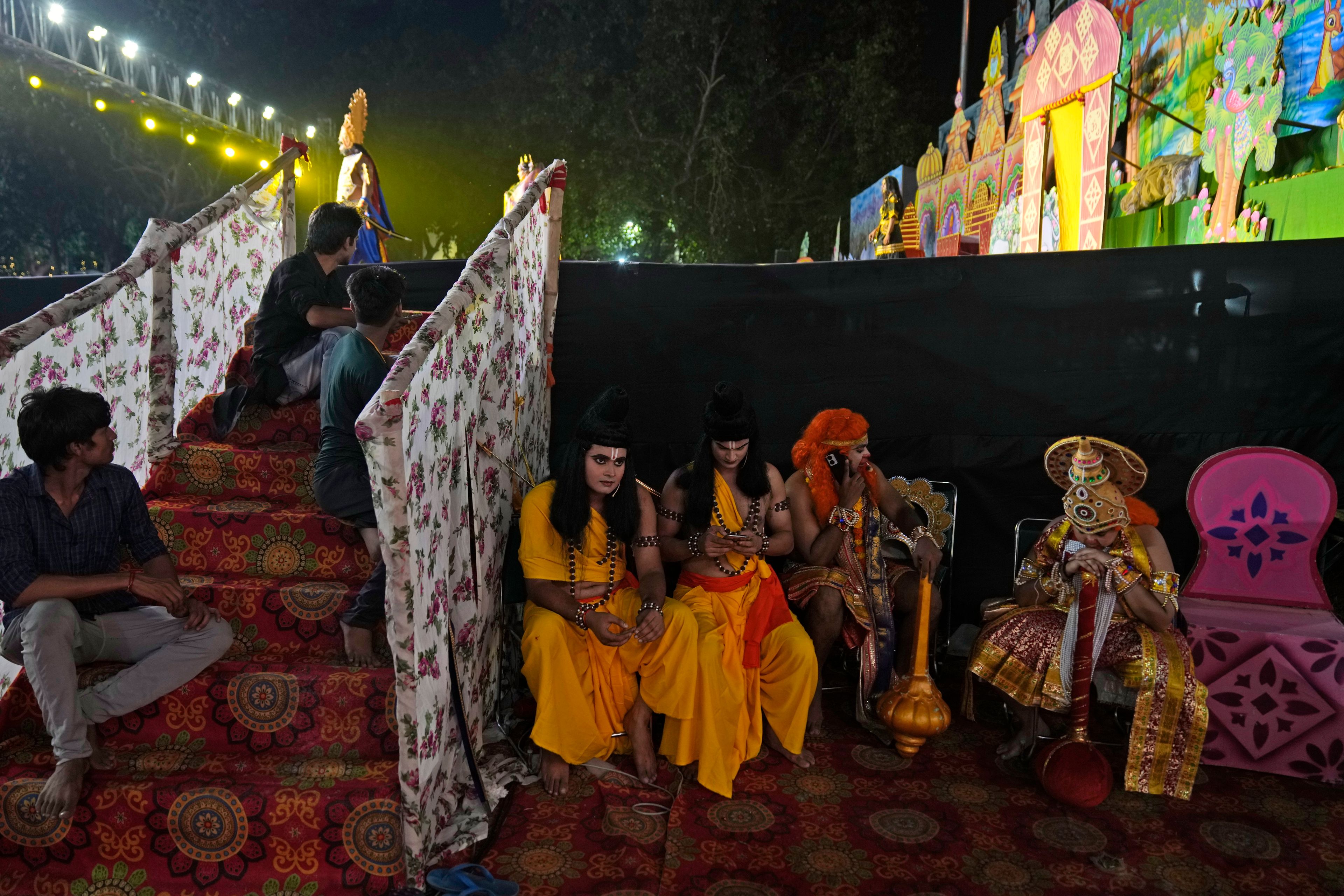 Ashutosh Agnihotri, 23, playing the character of Hindu god Rama, sitting to the right of the partition, waits with others to go onstage during Ramleela, a dramatic folk re-enactment of the life of Rama according to the ancient Hindu epic Ramayana, in New Delhi, India, Thursday, Oct. 10, 2024. (AP Photo/Manish Swarup)