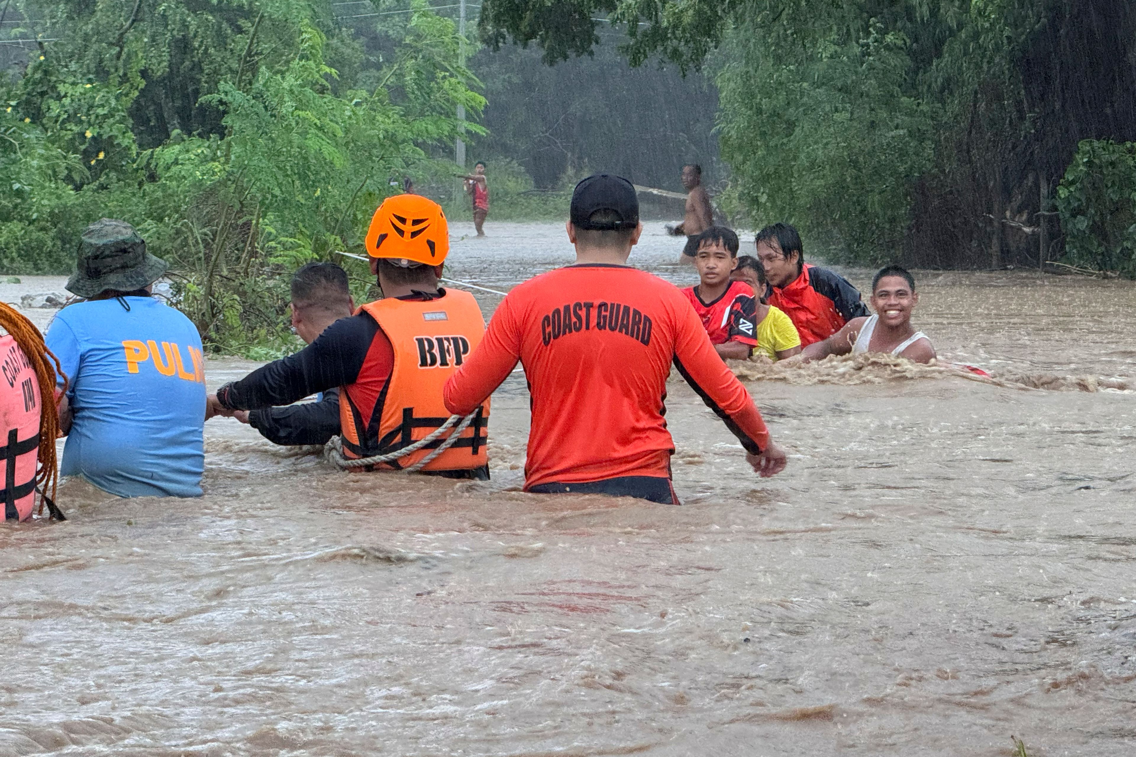 Rescuers help residents evacuate to higher grounds as they negotiate floods caused by powerful Typhoon Krathon locally called "Typhoon Julian" at Bacarra, Ilocos Norte province, northern Philippines on Monday, Sept. 30, 2024. (AP Photo/Bernie Dela Cruz)