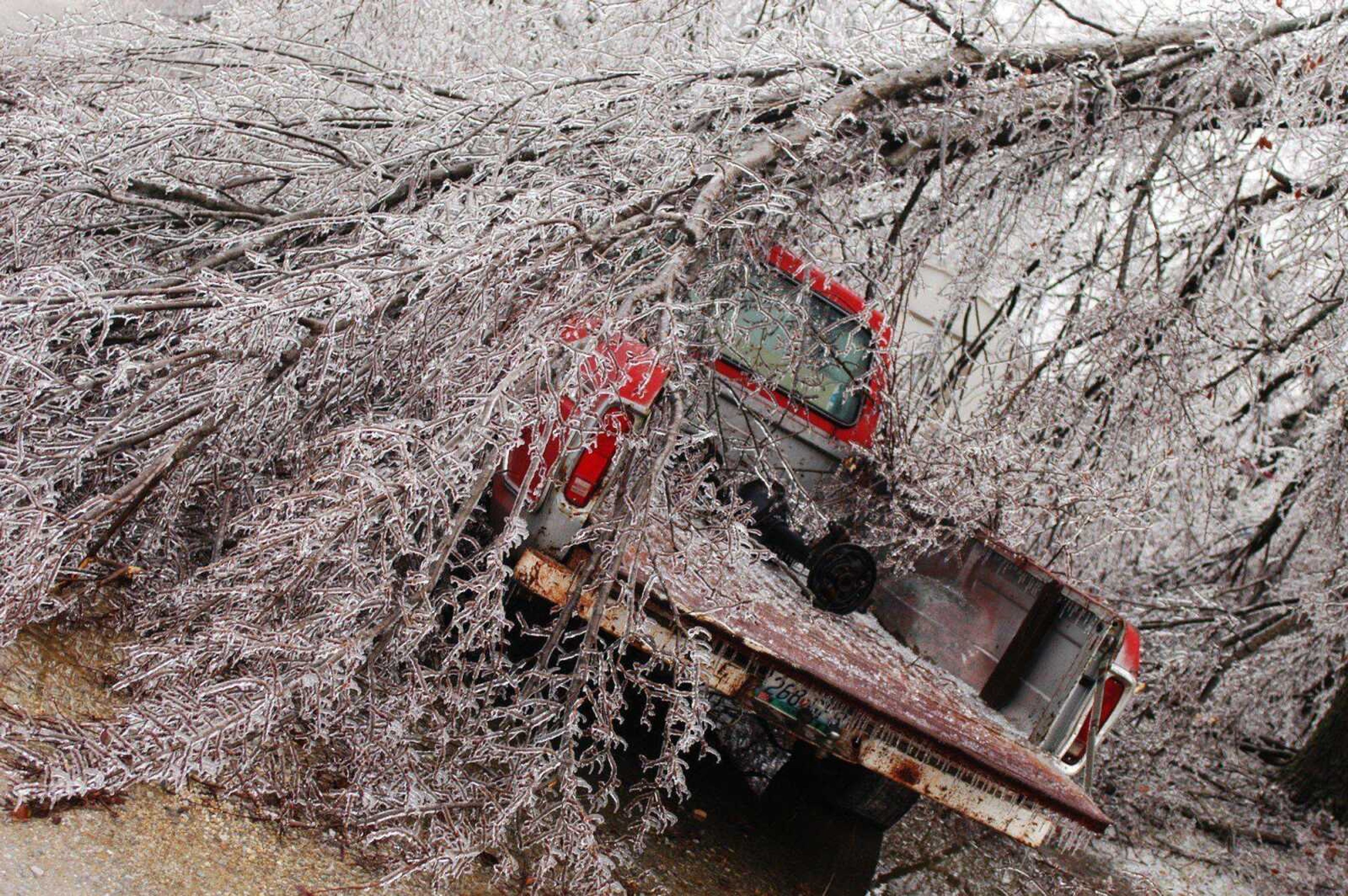 An ice-covered tree fell on a pickup truck Sunday in Joplin, Mo. An ice storm downed trees and power lines in southwest Missouri and southeast Kansas, leaving many residents without power. (MIKE GULLETT ~ Associated Press)