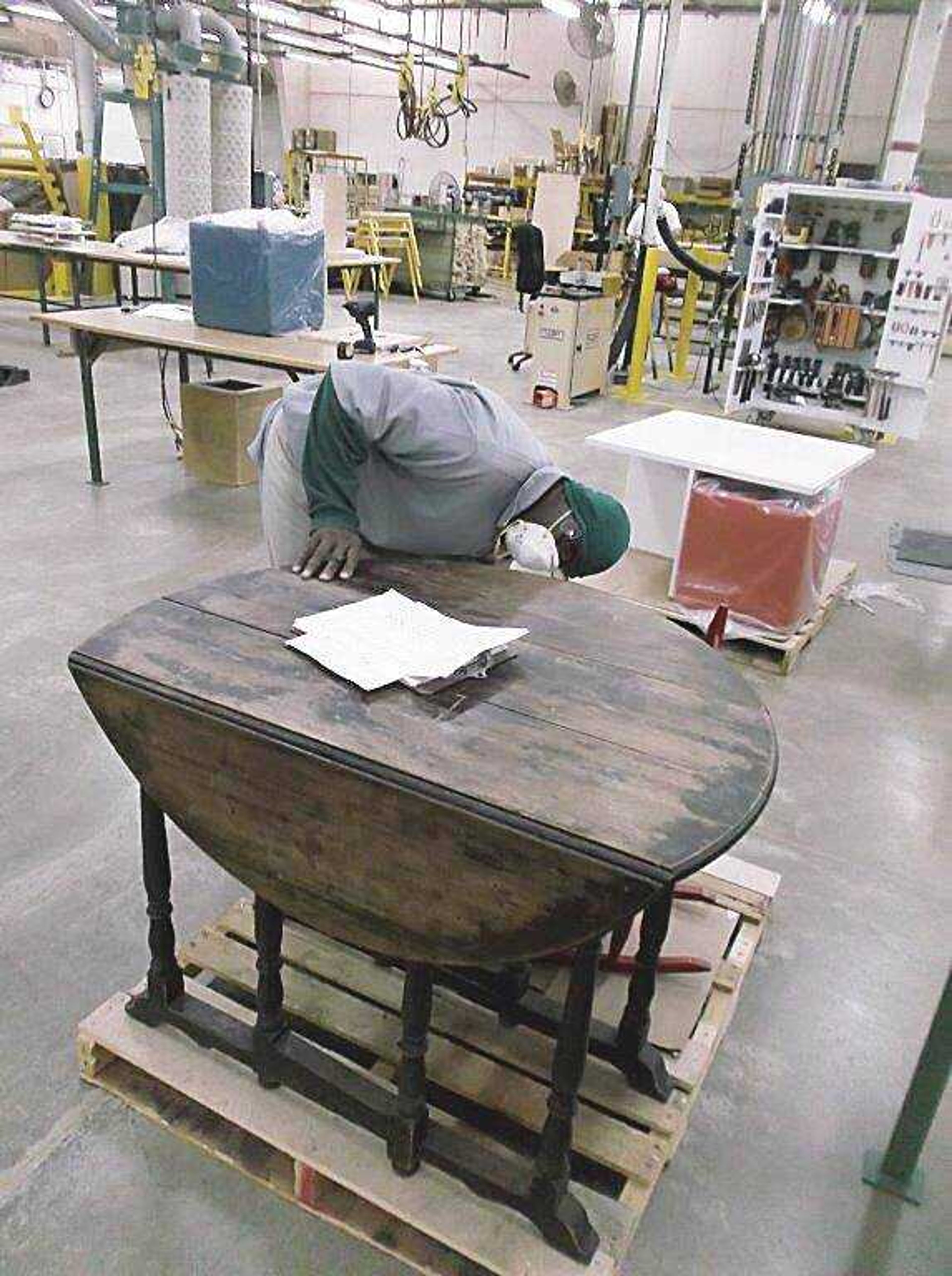 Willie Henderson, factory floor lead man, inspects a table received from a customer before workers restore it. Henderson has worked with Missouri Vocational Enterprises for 16 years and began in the payroll department. 