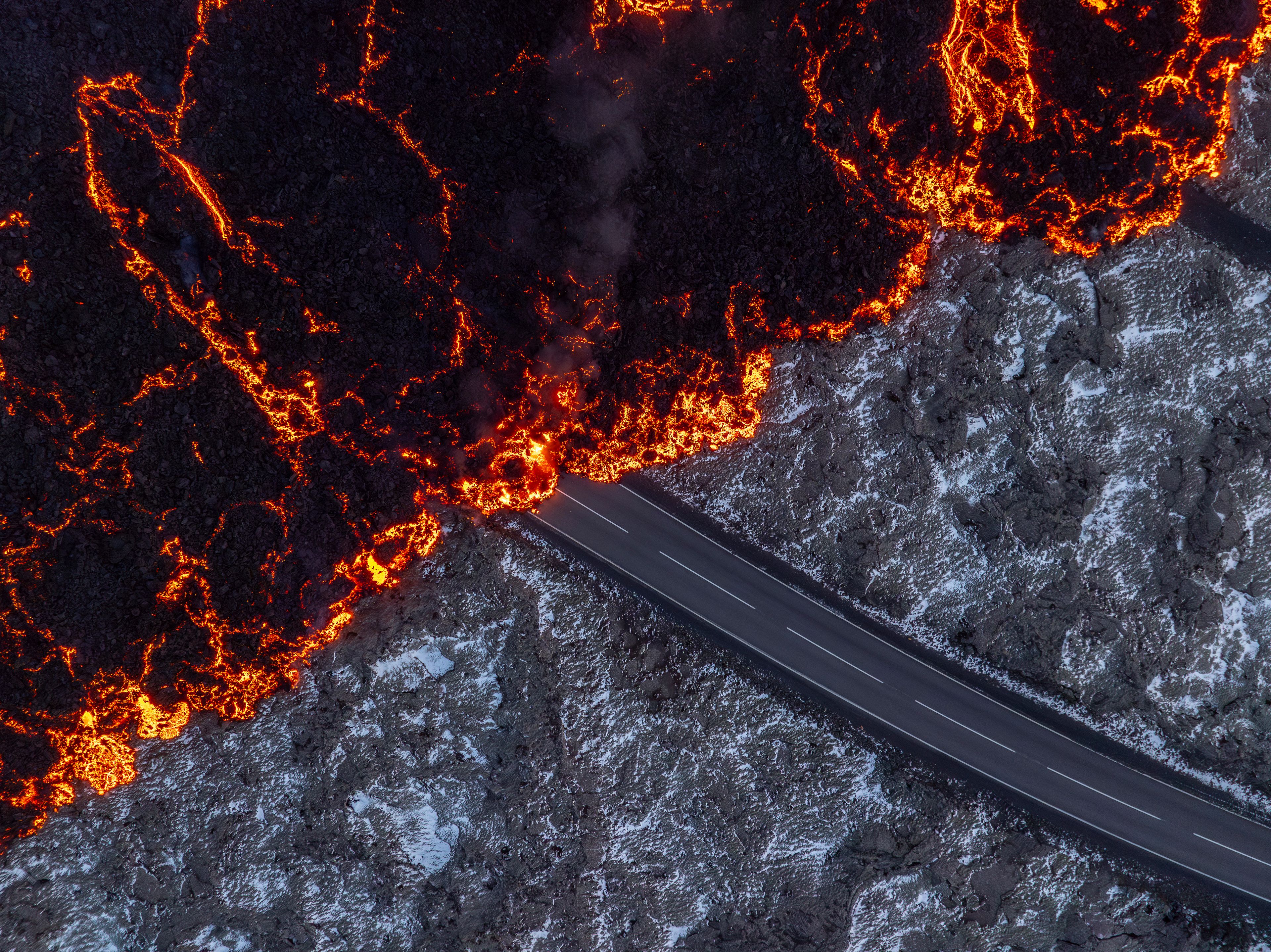 Molten lava flows on the road to the Blue Lagoon, Grindavik, after the volcanic eruption that started Wednesday, on the Reykjanes Peninsula in Iceland, Thursday, Nov. 21, 2024. (AP Photo/Marco di Marco)