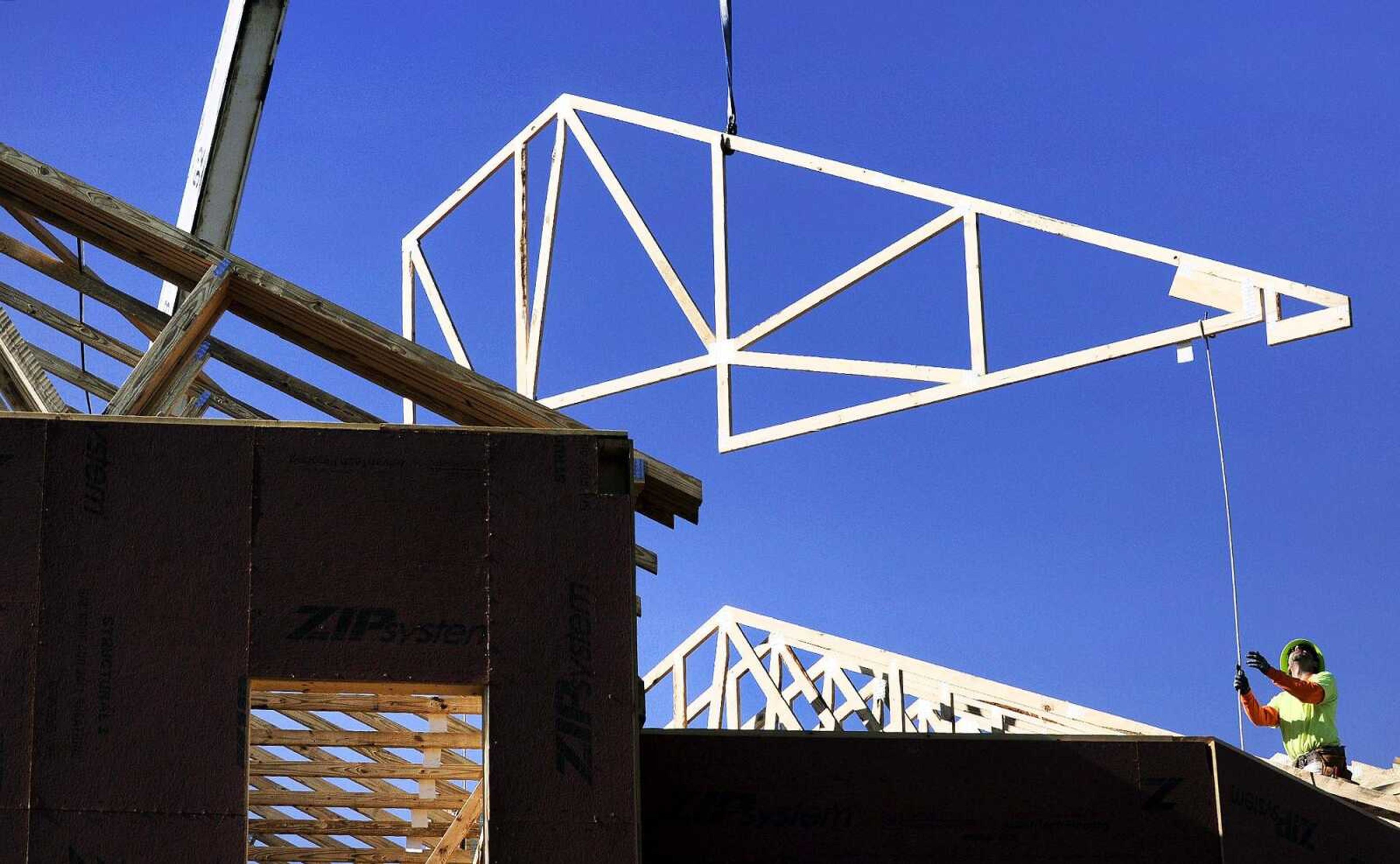 A worker helps guide a truss as it is lowered by a crane Monday to a building at Southeast Missouri State University's new Greek Village in Cape Girardeau.