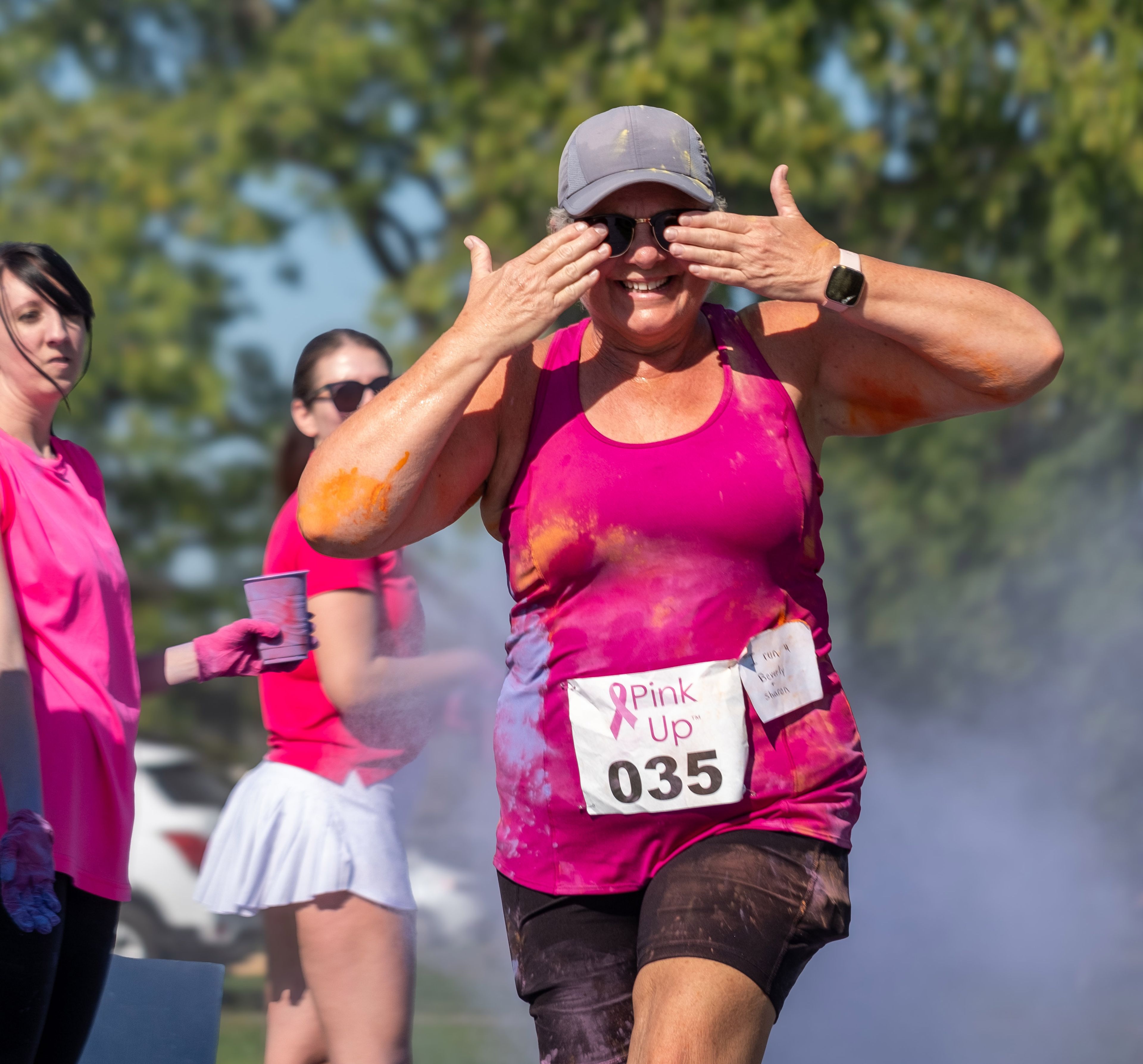 Deborah Pool from Marble Hill shields her eyes from the dust while running in tribute to her two friends who have triumphed over breast cancer.
