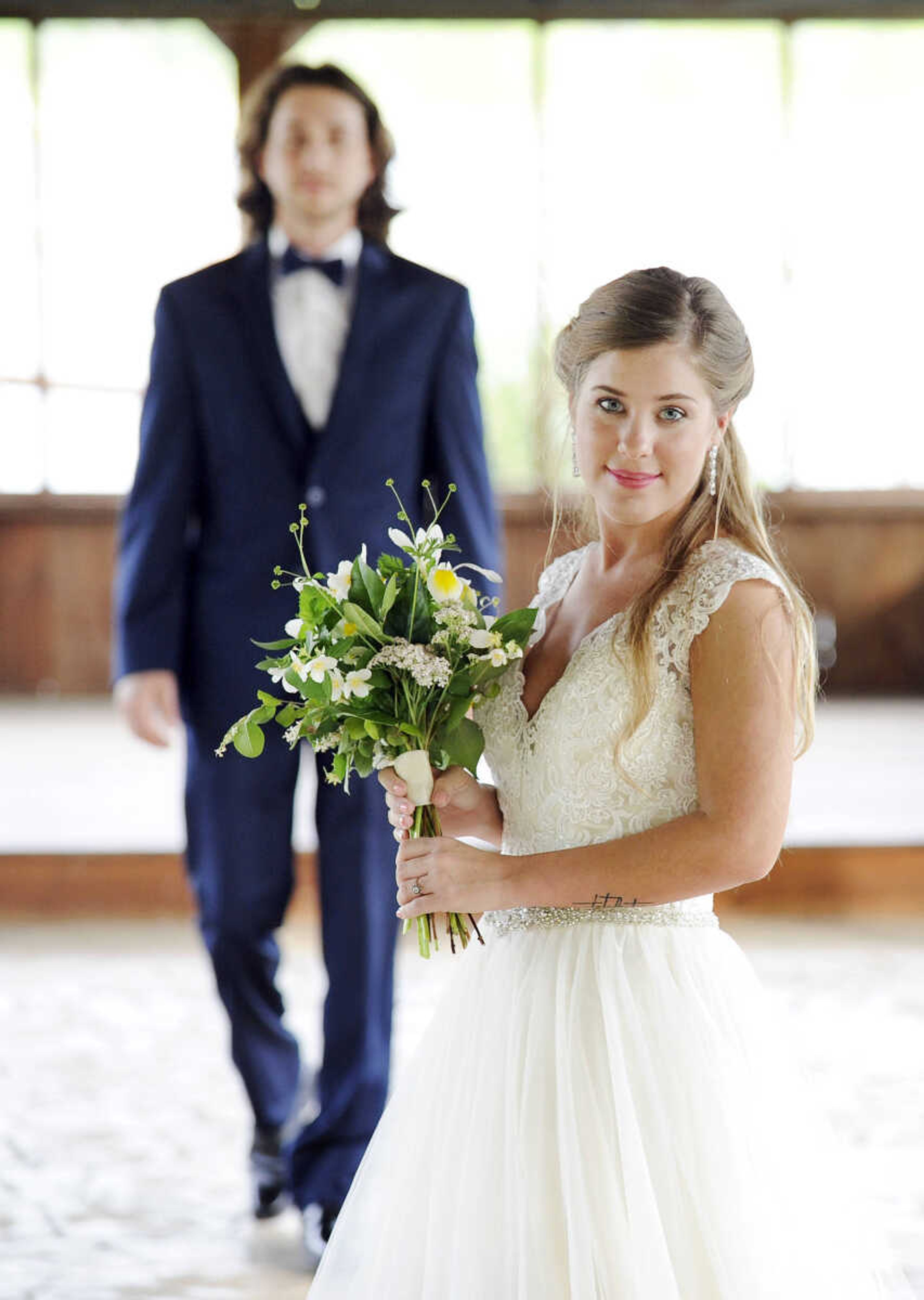 On Lydia: Allure Bridals gown in ivory with tulle skirt, lace bodice, beaded waste and button-back closure. Drop earrings by Jim Ball. All available at Joy's Bridal in Sikeston, Missouri. 

On Evan: Navy Sterling slim fit wedding suit by Michael Kors with navy plaid bow tie. Provided by Jim's Formal Wear and available at Garber's Men's Wear in Cape Girardeau.