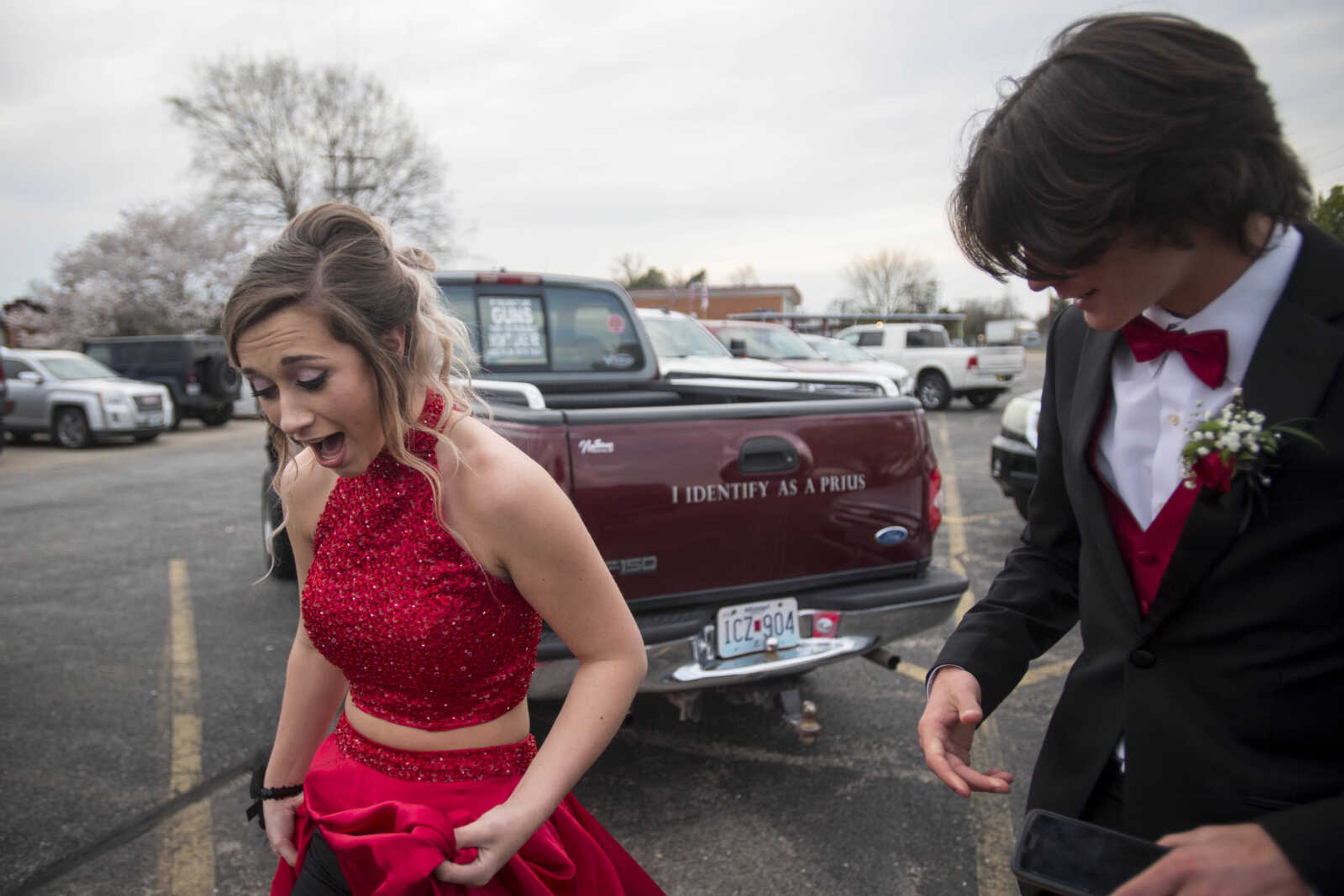 Having accidentally stepped on her hem, Kelly junior Andrea Richmond collects her dress before asking her date, Myles Trankler, right, to help her carry it the rest of the way across the parking lot before prom Saturday, April 6, 2019, at Kelly High School in Benton.