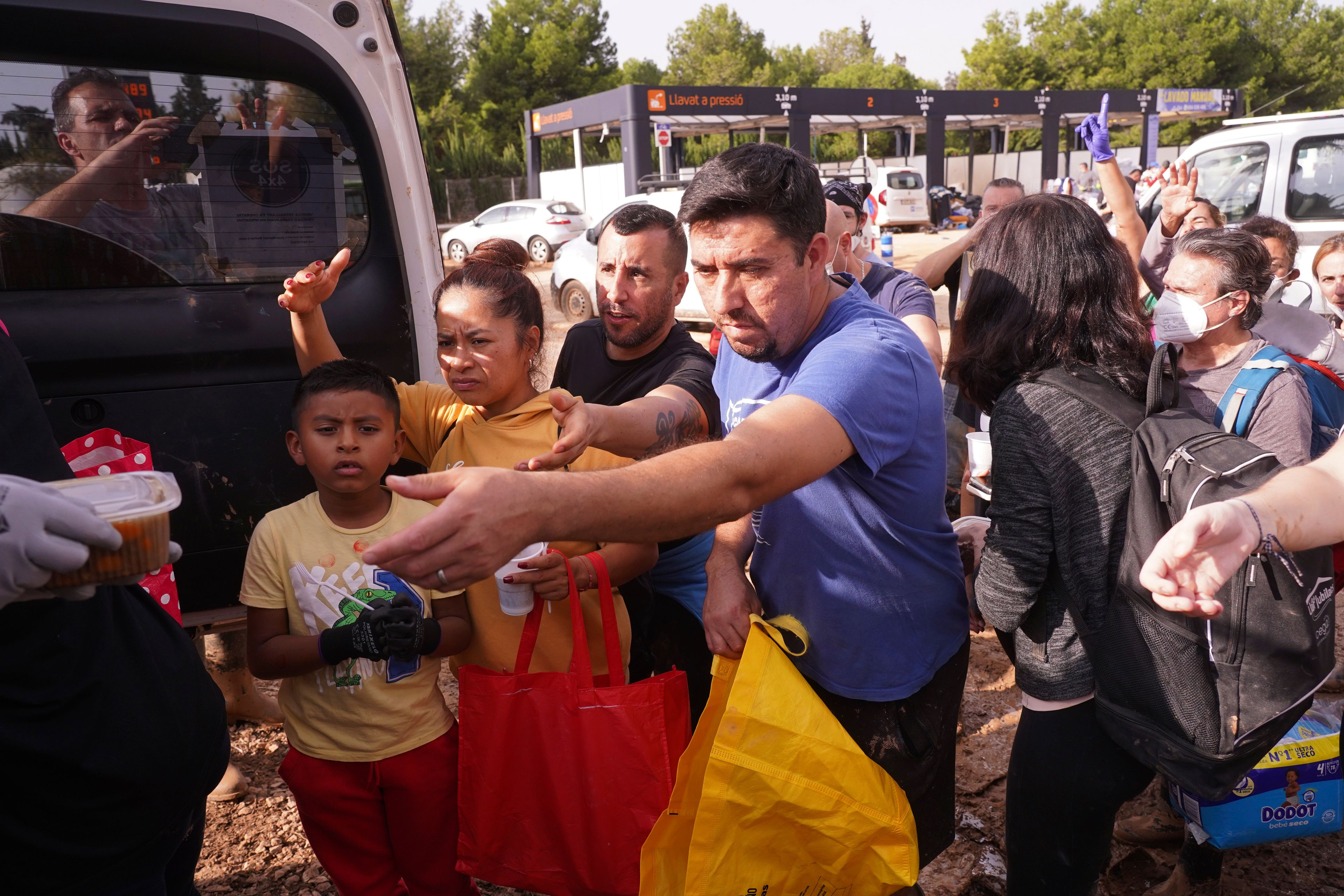 People are served hot food by volunteers from inside a vehicle after floods in Catarroja on the outskirts of Valencia, Spain, Tuesday, Nov. 5, 2024. (AP Photo/Alberto Saiz)