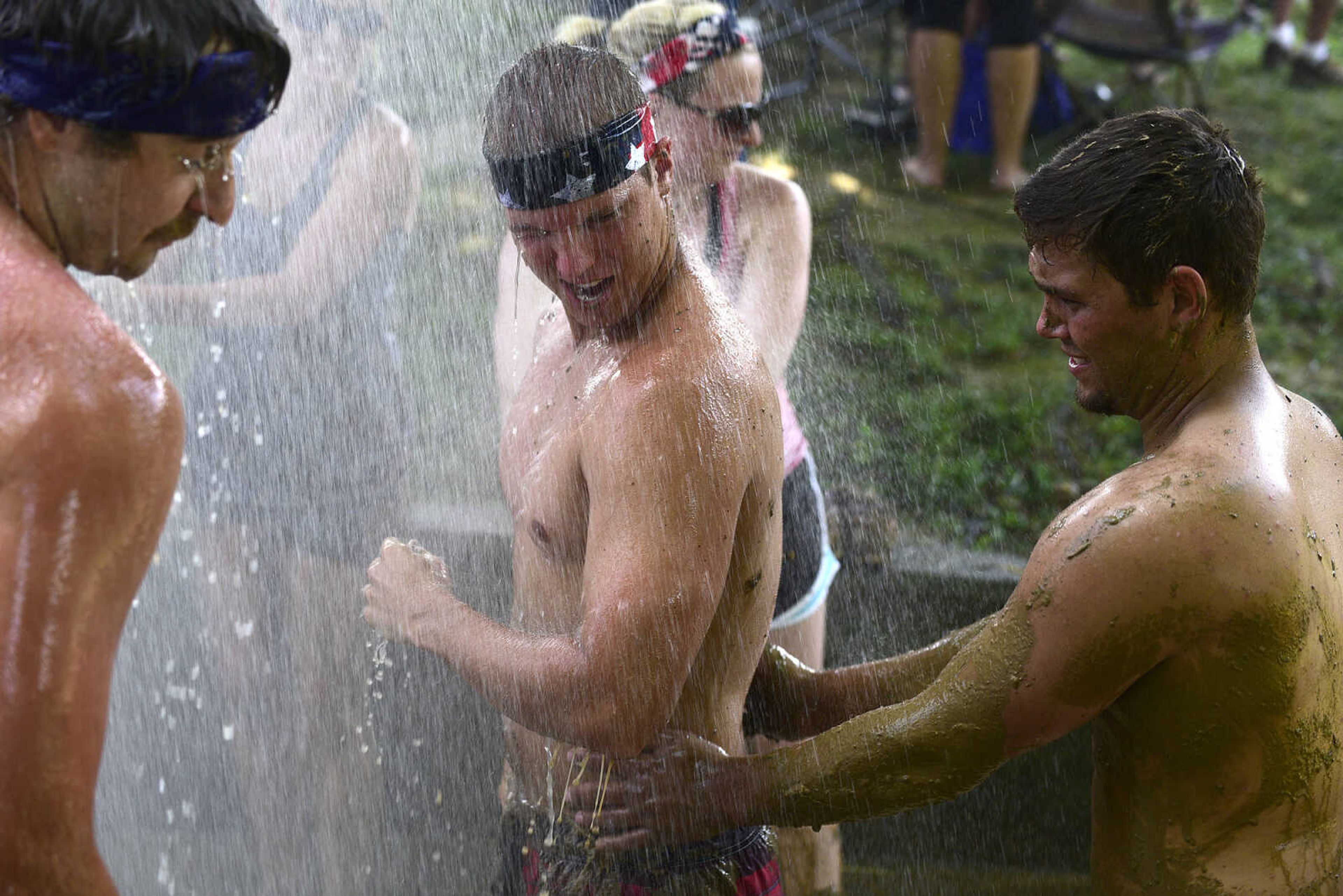 Team members hit the wash station after playing mud volleyball during the Fourth of July celebration on Tuesday at Jackson City Park.