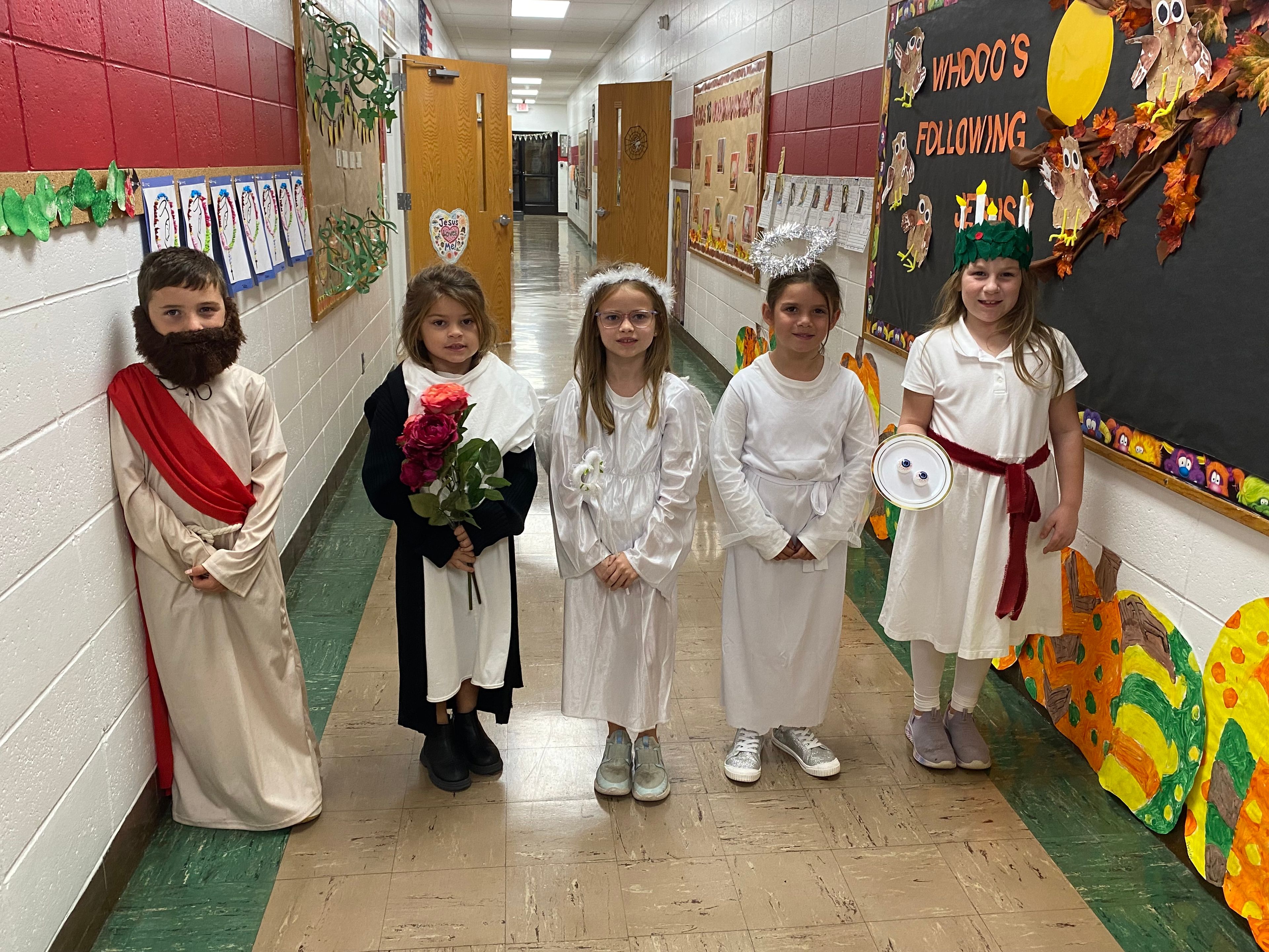 The first grade class saints included Jesus (August Graviett), St. Therese the Little Flower (Sadie Seyer), St. Gabriel the Archangel (Berkley Dennis), St. Raphael the Archangel (Caroline Eskew), and St. Lucy (Clara Vetter).