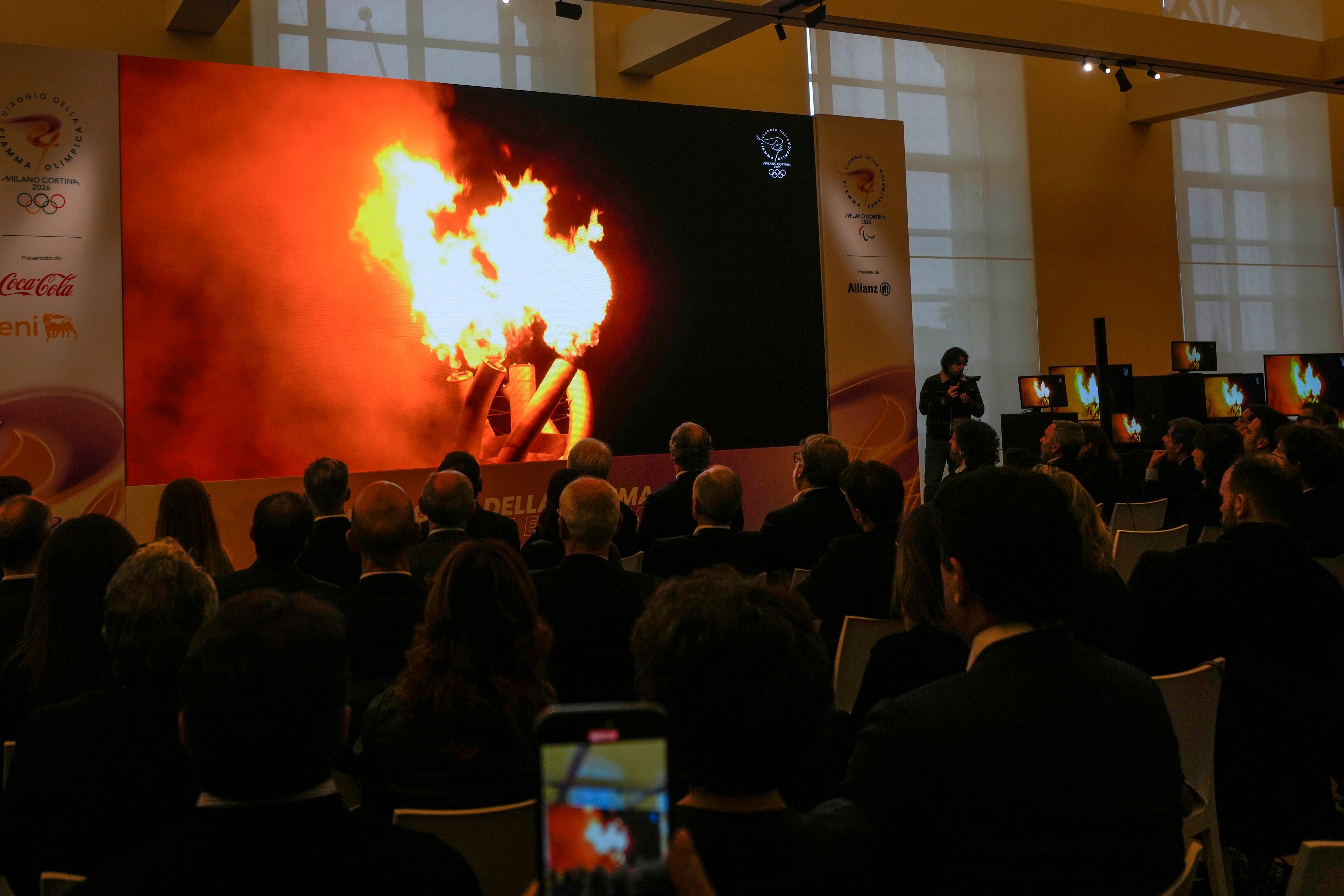 Reporters and guest watch a video on a screen during a news conference to present the 2026 Winter Olympics and Paralympics torch route, in Verona, Italy, Tuesday, Nov. 26, 2024. (AP Photo/Luca Bruno)