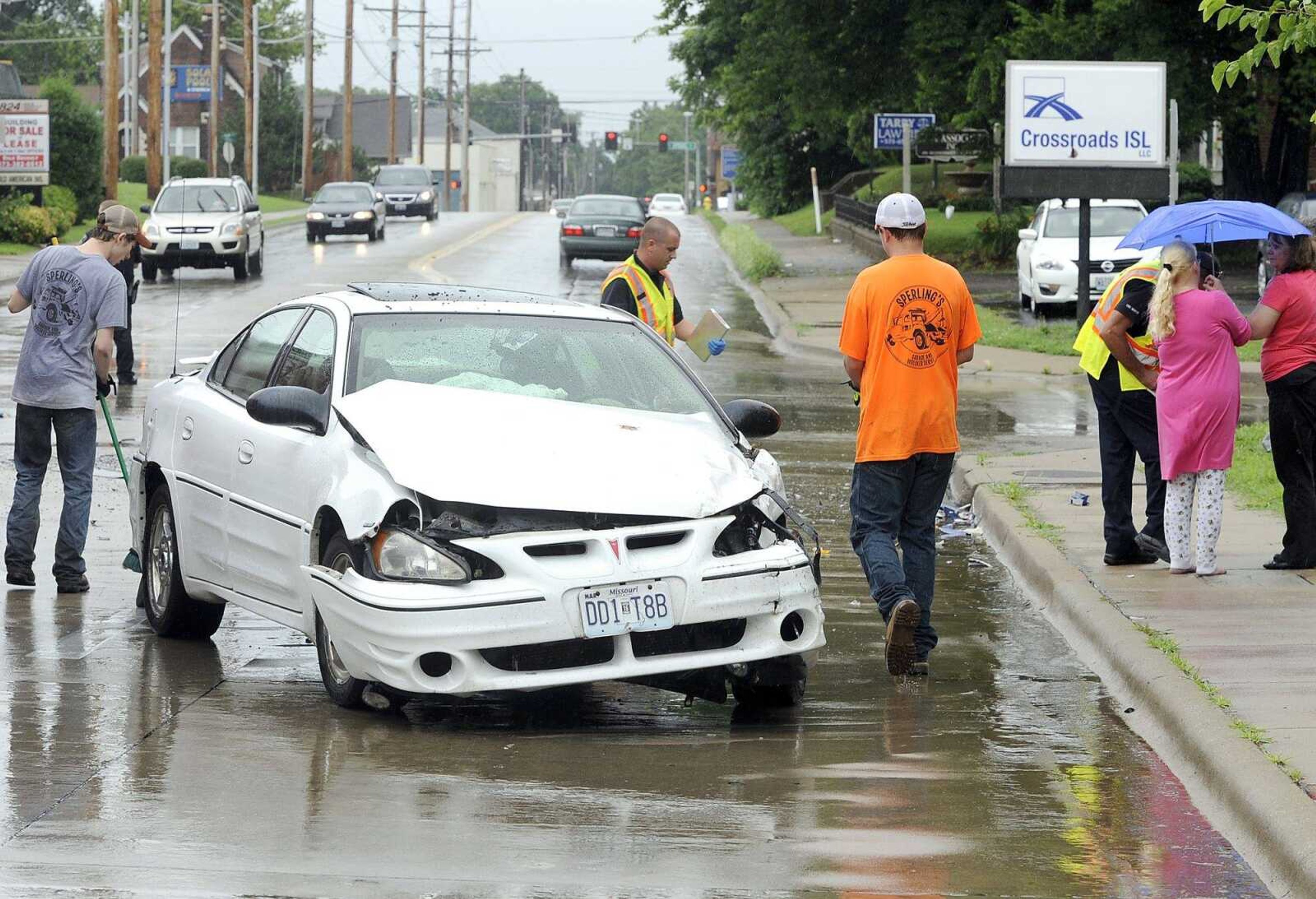 Workers clear an accident Friday, June 19, 2015, which involved a white Pontiac Grand Am GT and a Lincoln Navigator at Independence and Pacific streets in Cape Girardeau. Police cited the driver of the Grand Am for failure to yield. (Fred Lynch)