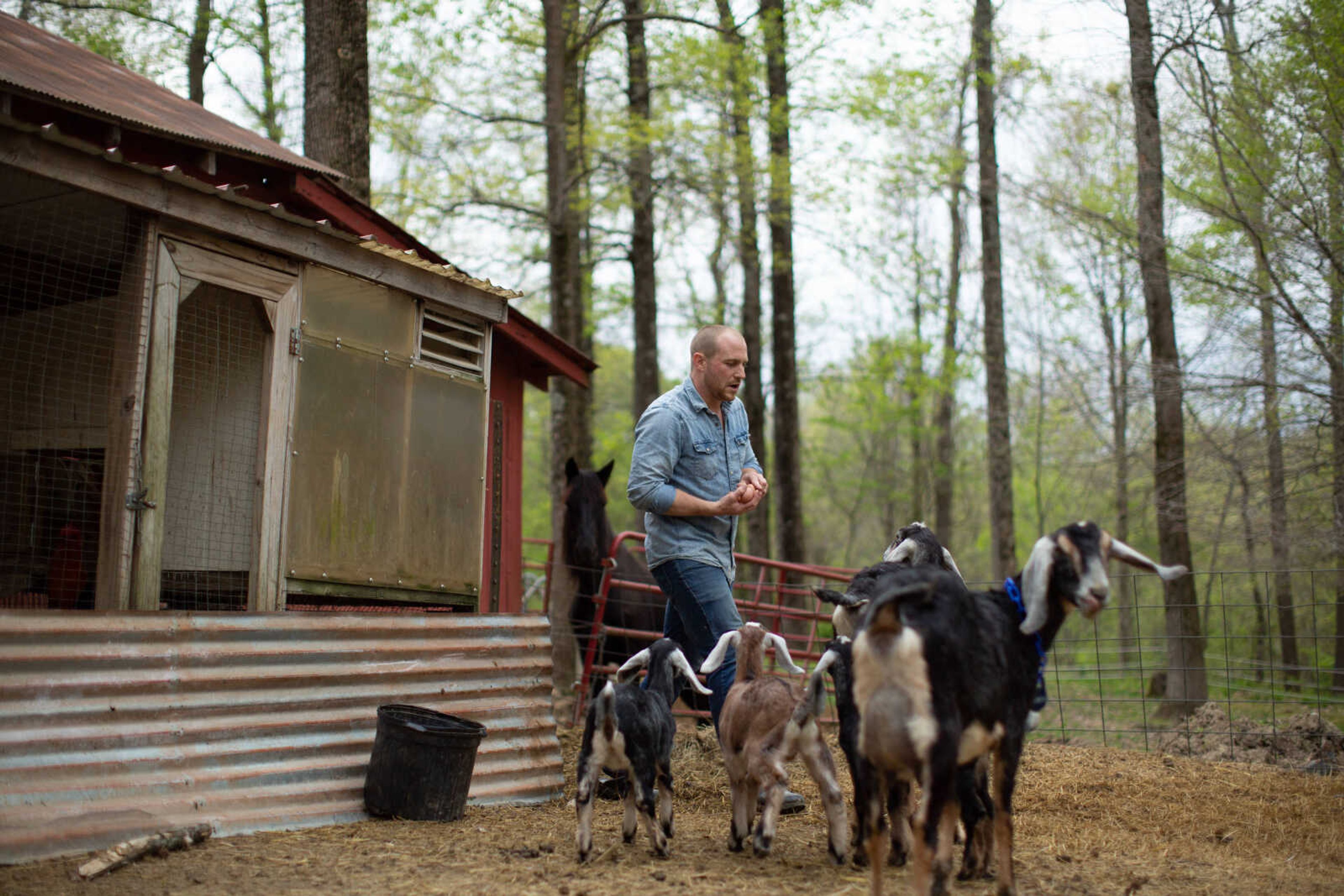 Trever Duncan carries a handful of fresh eggs from the chicken coup, surrounded by his other animals. After enjoying raising goats when he was younger, Trever got back into the hobby during the pandemic.