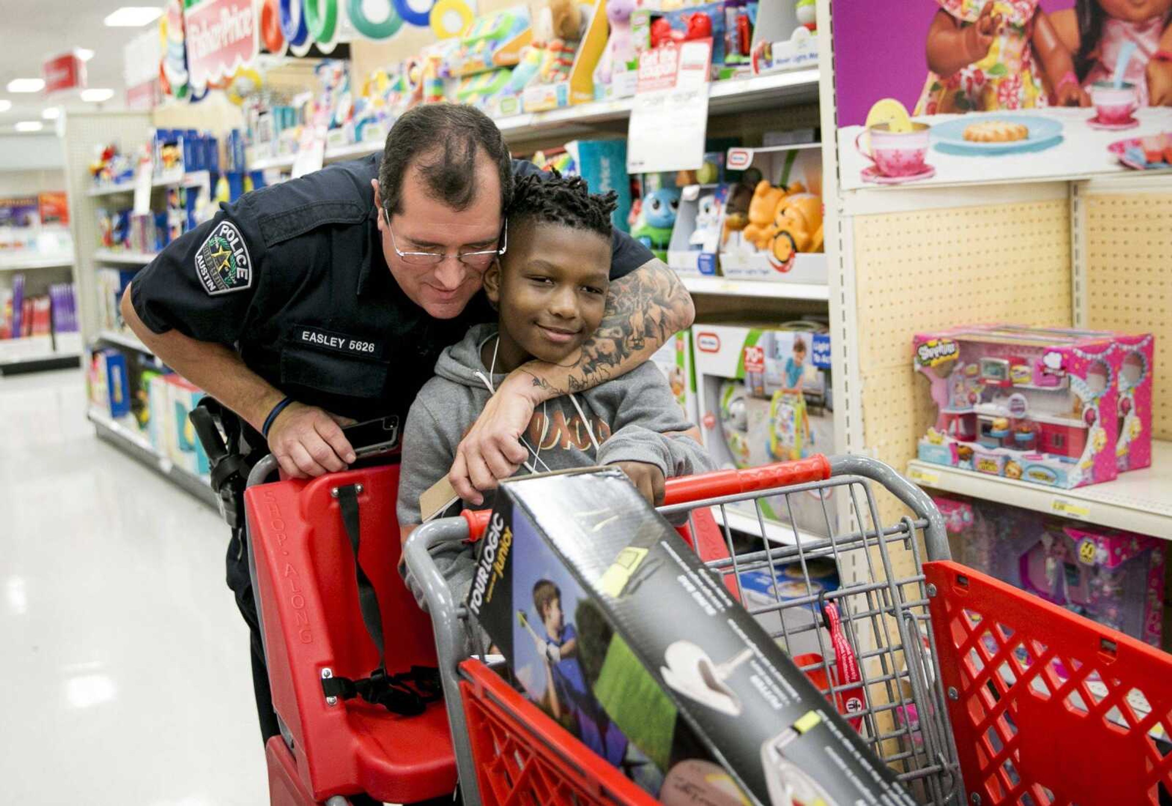 Austin police officer David Easley puts a tattooed arm around Jarvis Moblin, 8, in a hug during the 14th annual Shop With A Cop shopping spree Dec. 15 at a Target in Austin, Texas. Police departments, compelled by a hiring crisis and eager for a more diverse applicant pool, are relaxing traditional grooming standards and getting away from rules that used to require a uniformly clean-shaven, 1950s look.