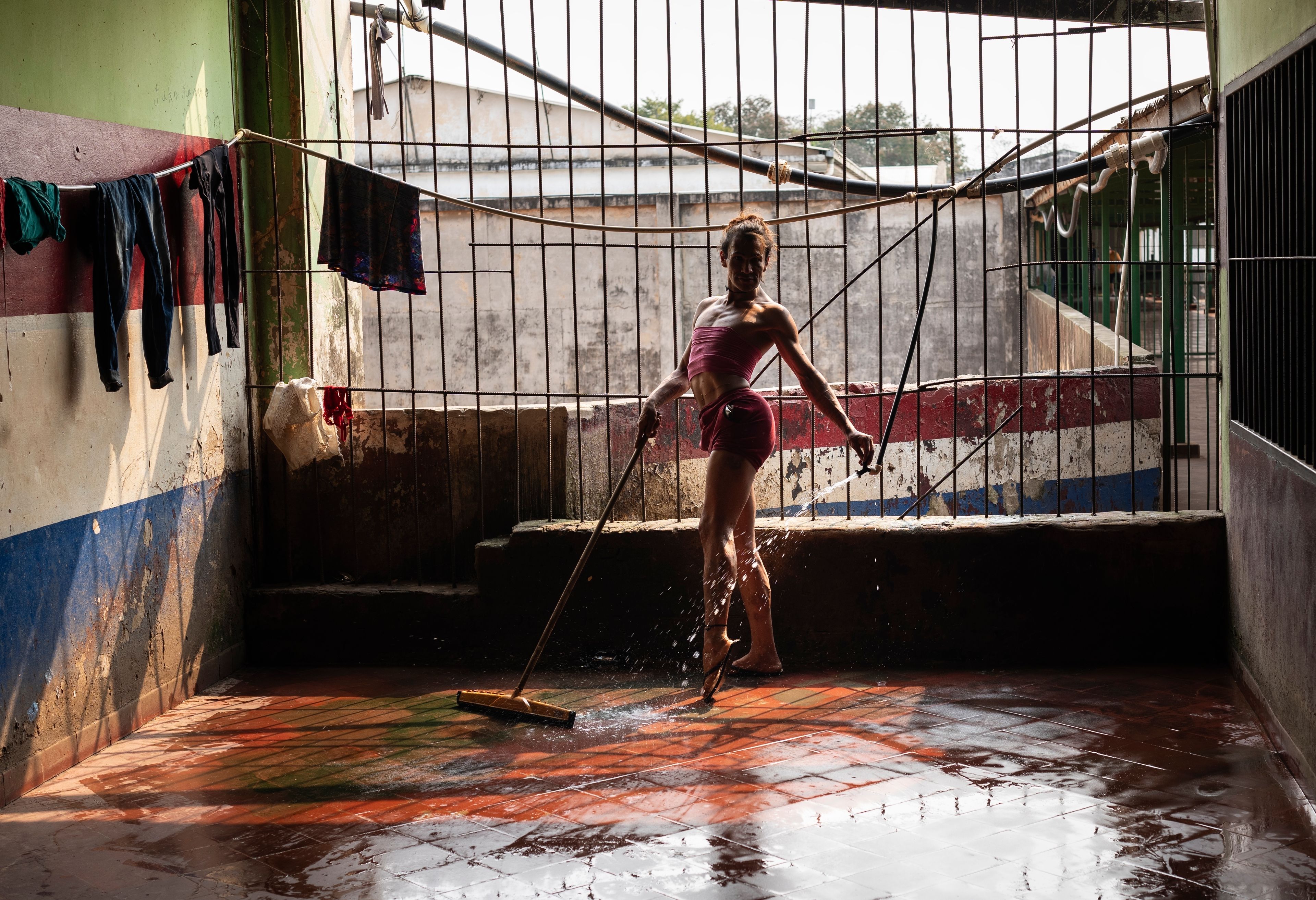 Magali Vargas, 29, strikes a pose while cleaning the floor of the pavilion reserved for transgender inmates at the Regional Penitentiary in Coronel Oviedo, Paraguay, Friday, Aug. 30, 2024. (AP Photo/Rodrigo Abd)