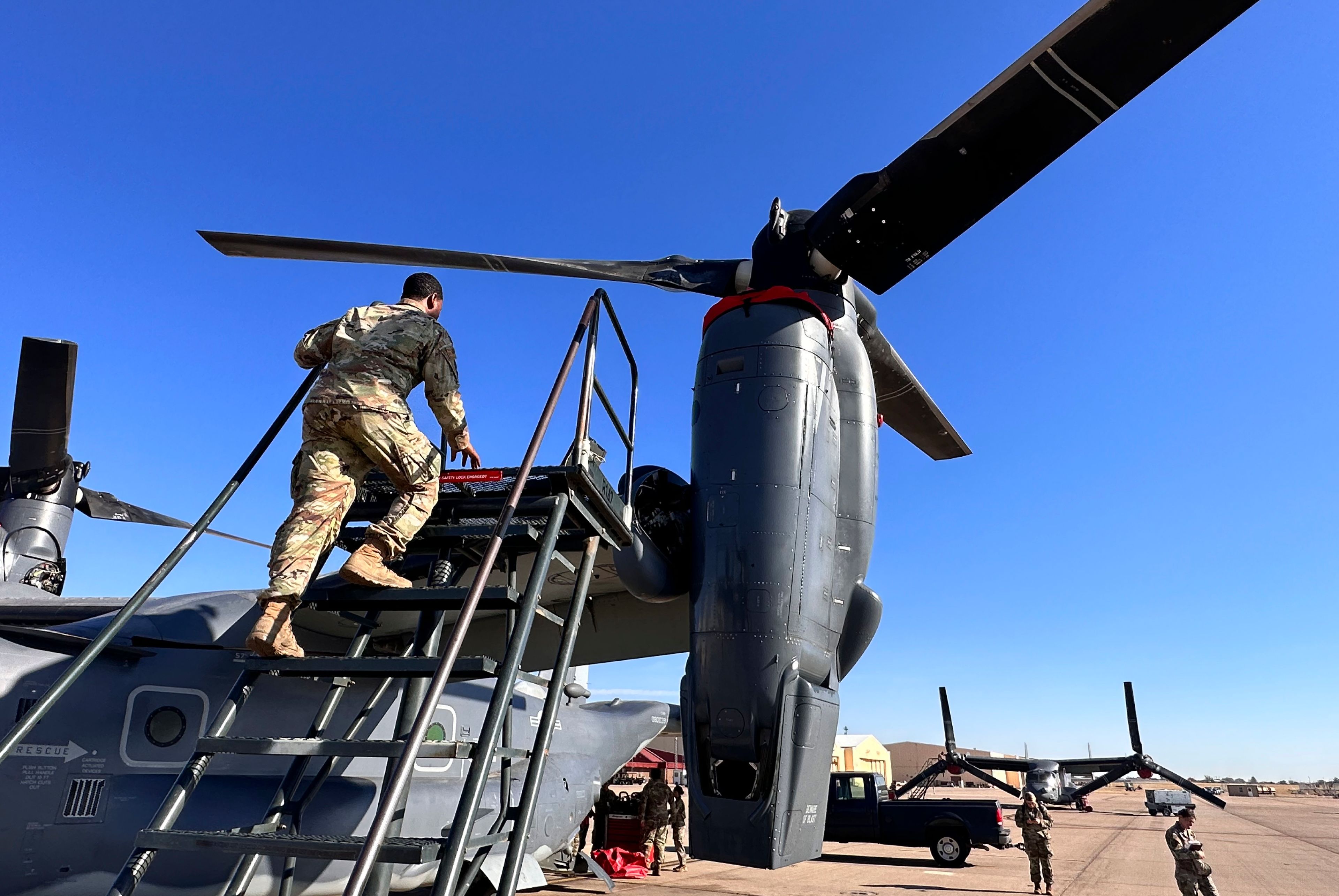 Master Sgt. Frank Williams, the production superintendent of the 20th Special Operations aircraft maintenance squadron at Cannon Air Force Base, N.M., climbs a ladder to show where hydraulic lines at the joint of the rotating engine and transmission need to be checked on the Osprey after flights, Oct. 8, 2024. (AP Photo/Tara Copp)