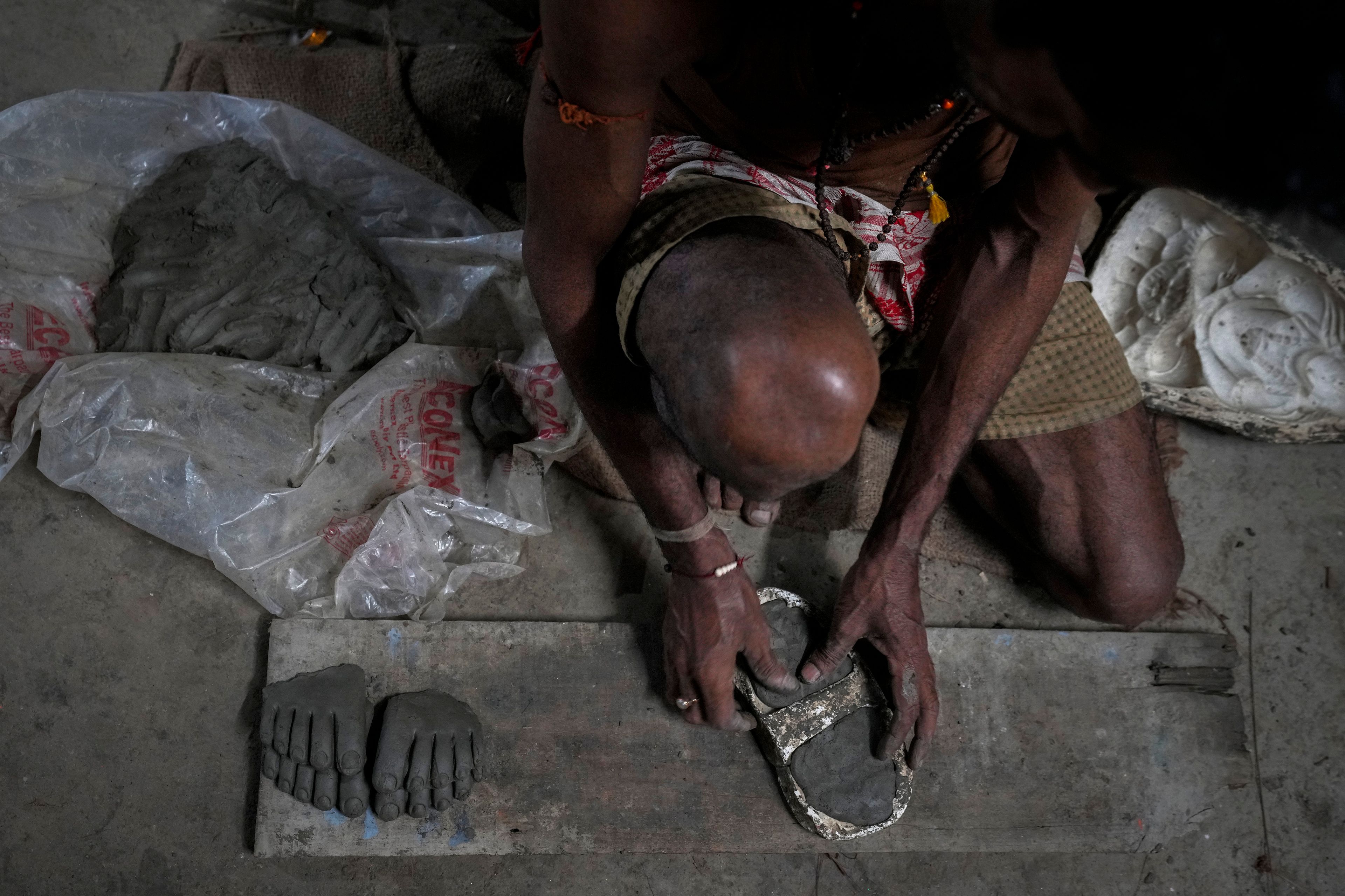 An artisan uses clay to form the toe end of the feet for a mud idol of the Hindu goddess Durga at a workshop during the Durga Puja festival in Guwahati, India, Friday, Oct. 4, 2024. (AP Photo/Anupam Nath)