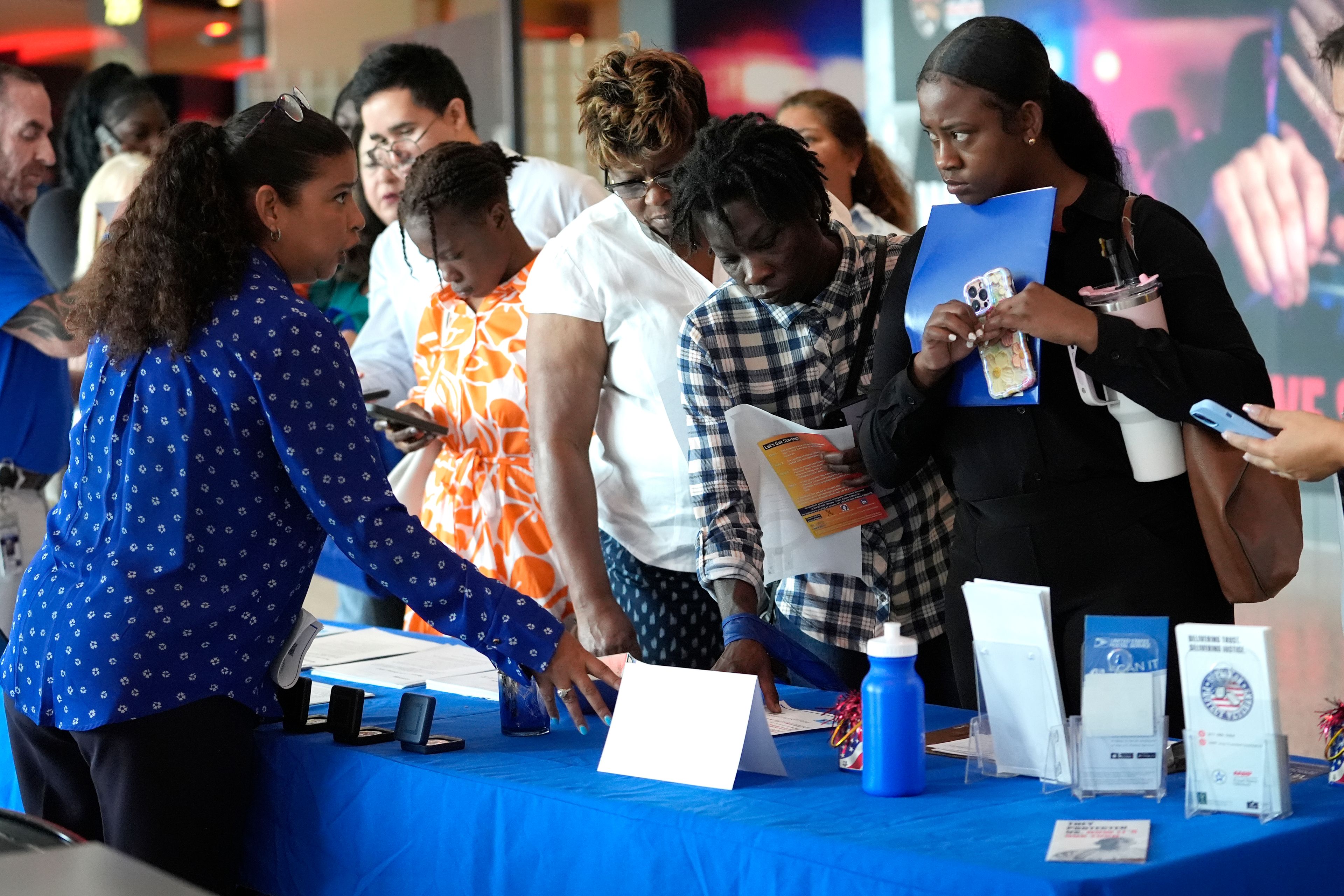 FILE - Carolina Wilson, with the United States Postal Service, left, talks with prospective job applicants at a job fair, Aug. 29, 2024, in Sunrise, Fla. (AP Photo/Lynne Sladky, File)