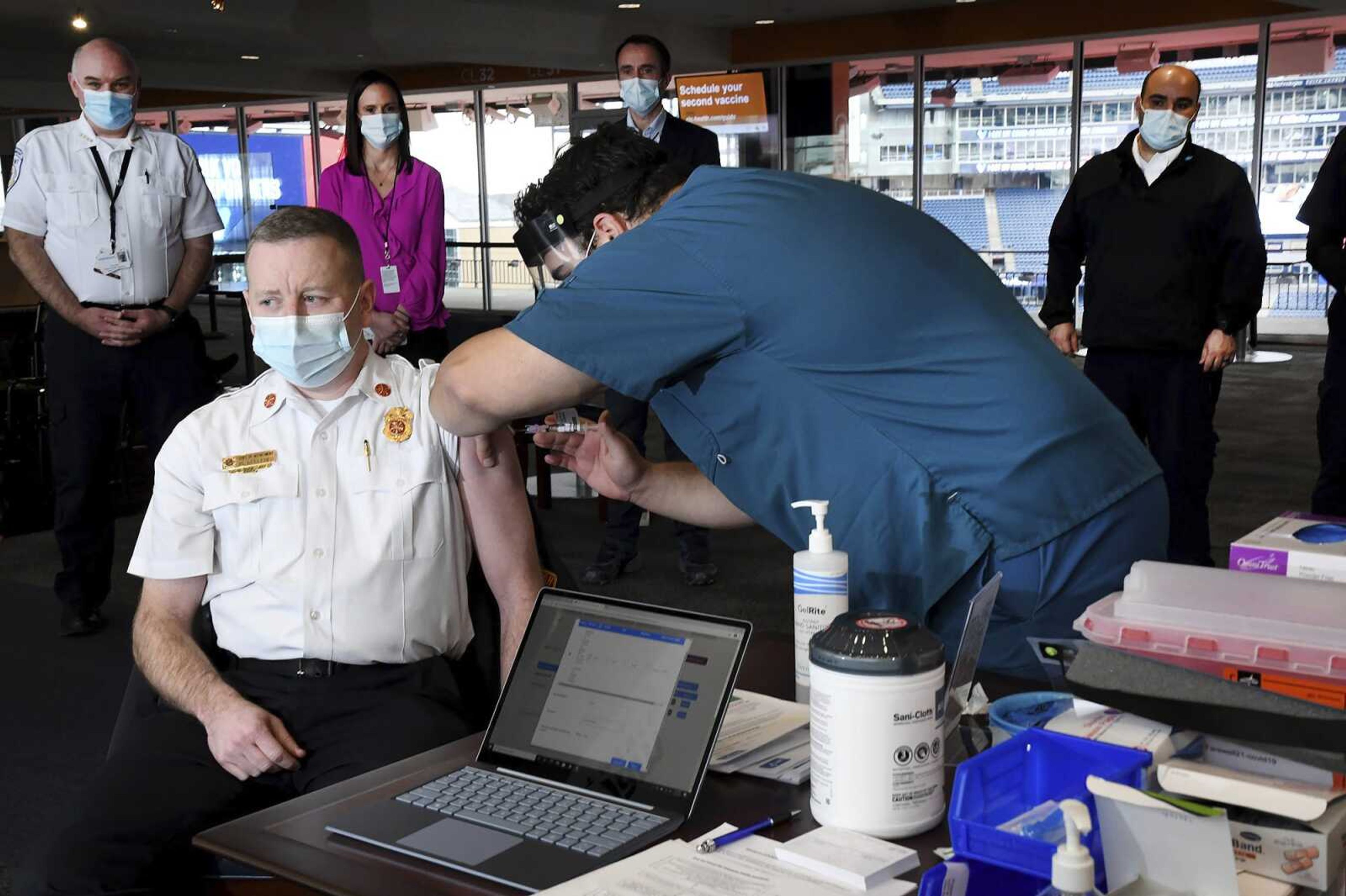 Foxboro Fire Chief Mike Kelleher is administered the Moderna vaccine in January by nurse Joshua Previte at the Putnam Clubhouse at Gillette Stadium in Foxboro, Massachusetts. The resurgence of COVID-19 this summer and the national debate over vaccine requirements have created a fraught situation for the nation's first responders, who are dying in larger numbers but pushing back against mandates.