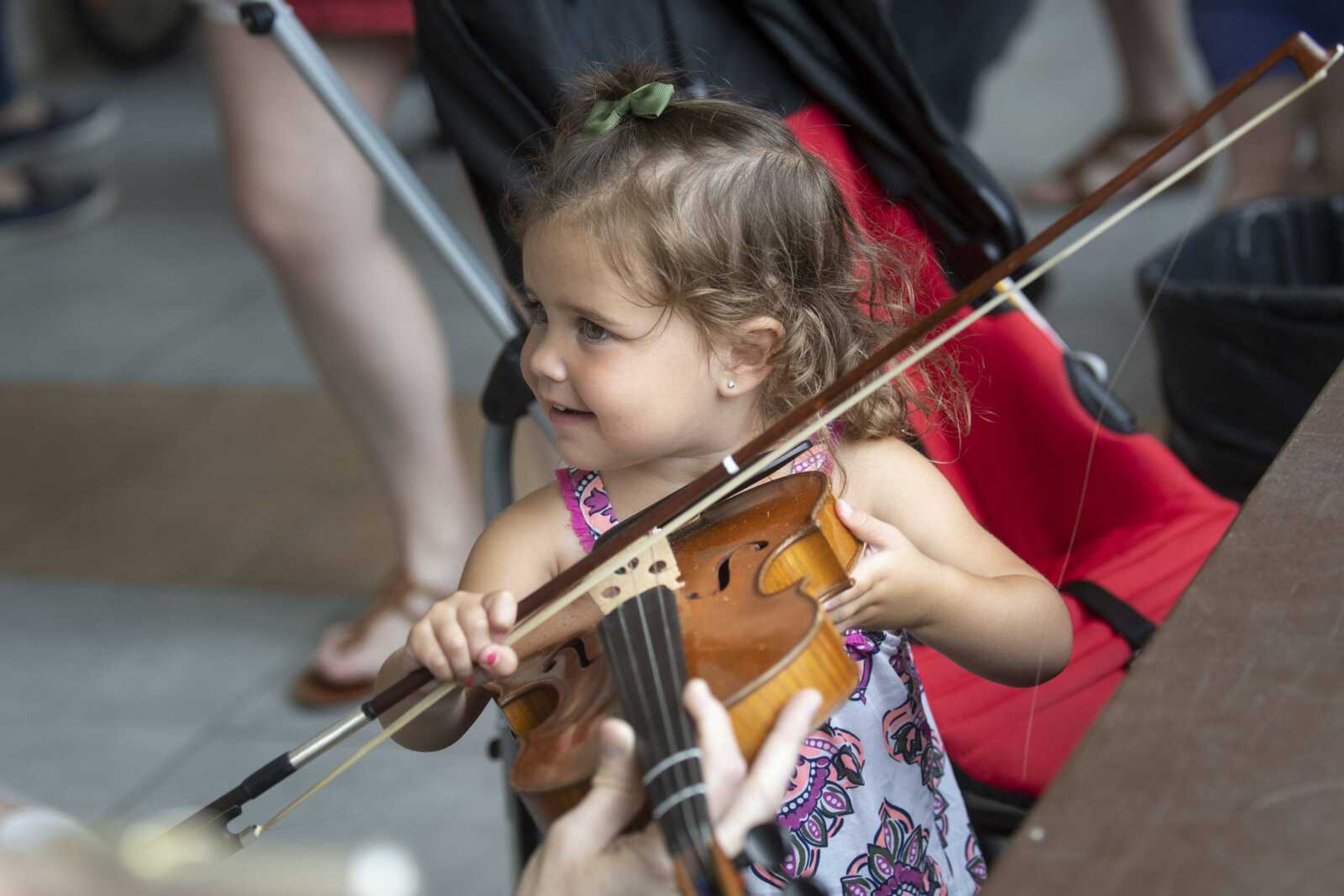 Colbie Raney, 3, of Jackson tries out an instrument during the Summer Arts Festival on Saturday at the Southeast Missouri State University River Campus in Cape Girardeau.