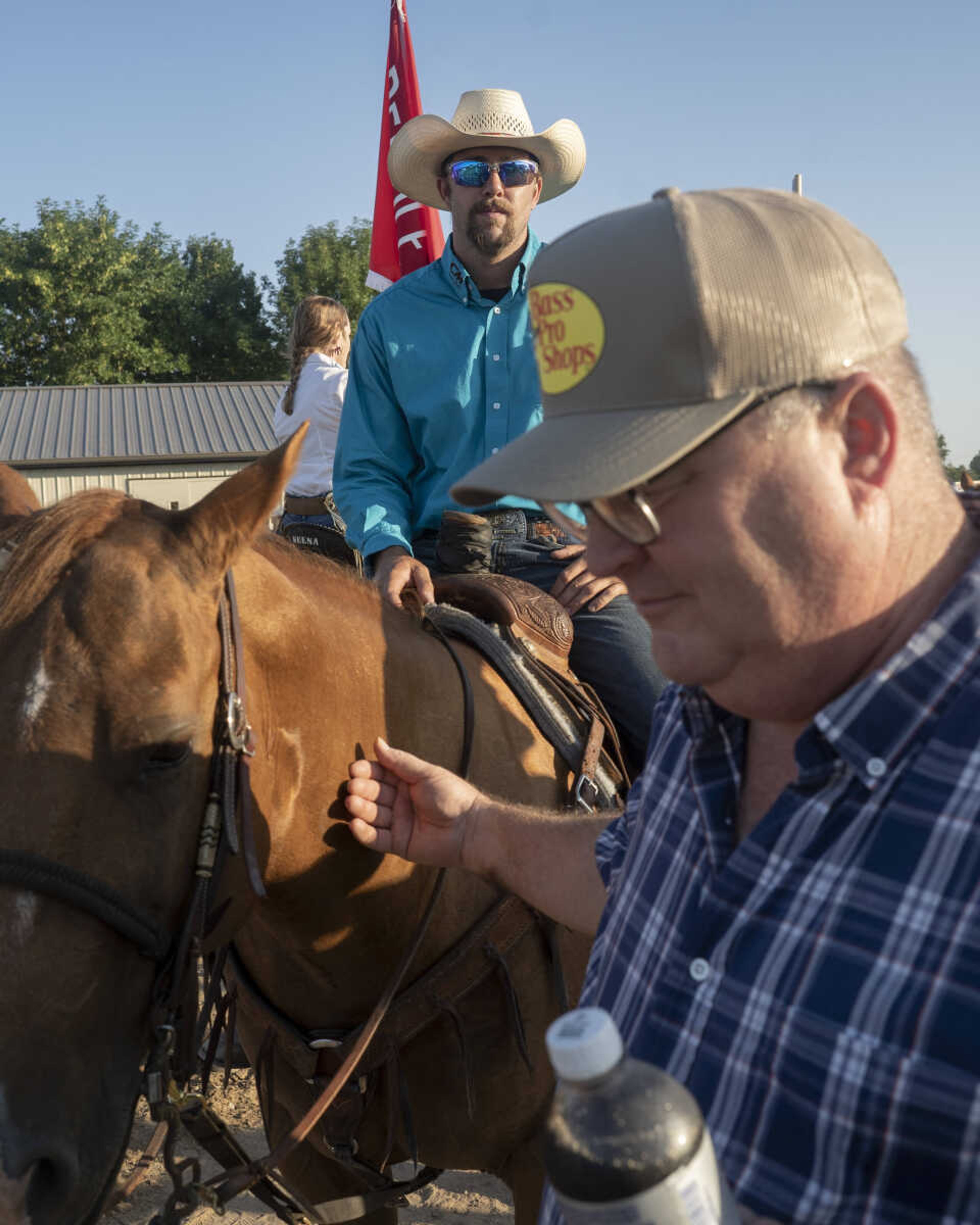 A friendly pedestrian pats Austin Curtis' horse as the  Sikeston Jaycees club president sits for a portrait before the opening ceremonies during the first night of the Sikeston Jaycee Bootheel Rodeo on Wednesday, Aug. 11, 2021, in Sikeston, Missouri.