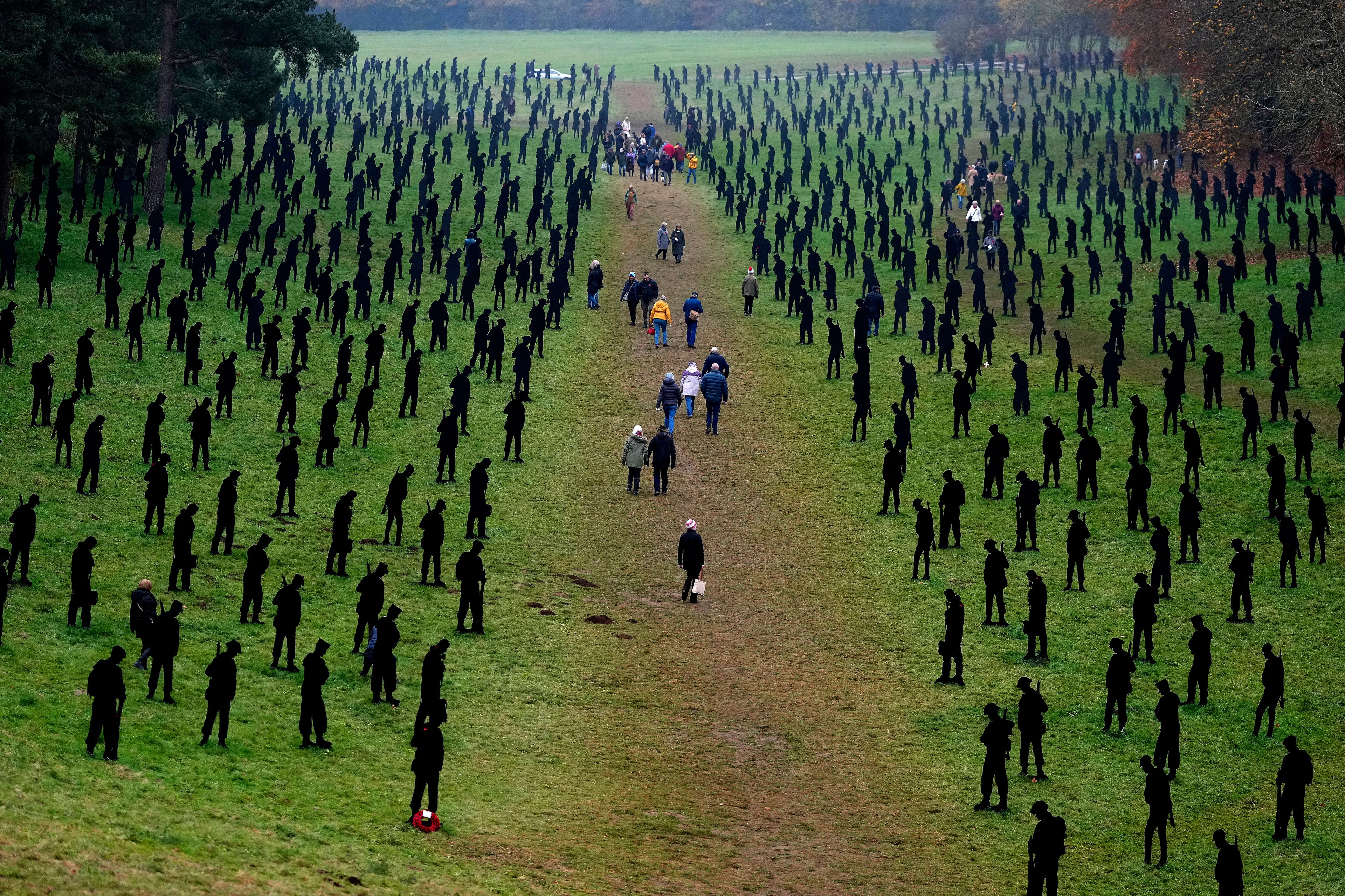 Visitors walk through the large-scale art installation, representing 1,475 silhouettes of Second World War military personnel, at Grecian Valley near Buckingham, England, Friday, Nov. 8, 2024. (AP Photo/Frank Augstein)