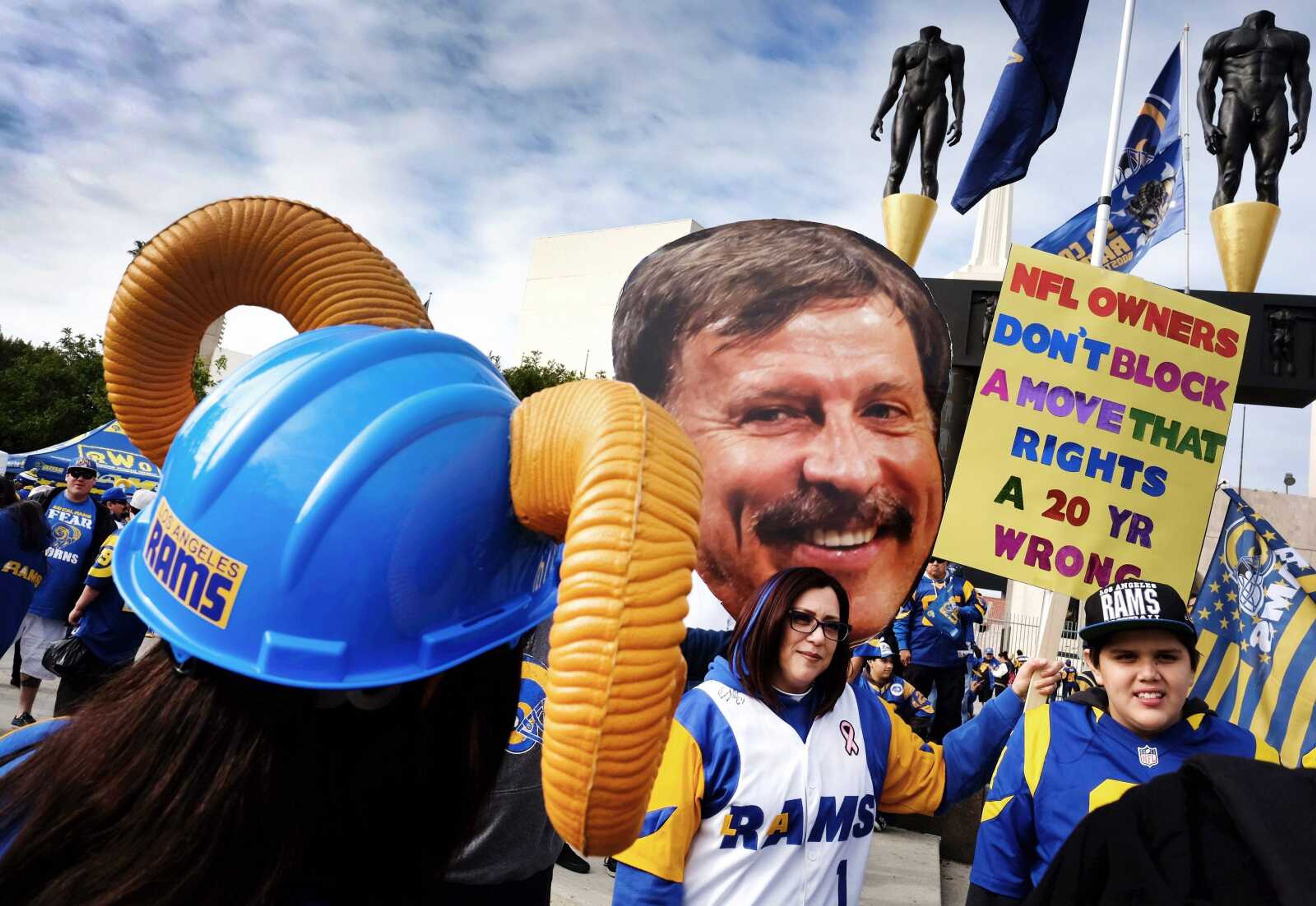 Rams fans pose Saturday in front of a photo of St. Louis Rams NFL football team owner Stan Kroenke, center, during a rally at the Los Angeles Memorial Coliseum. (AP Photo/Richard Vogel)