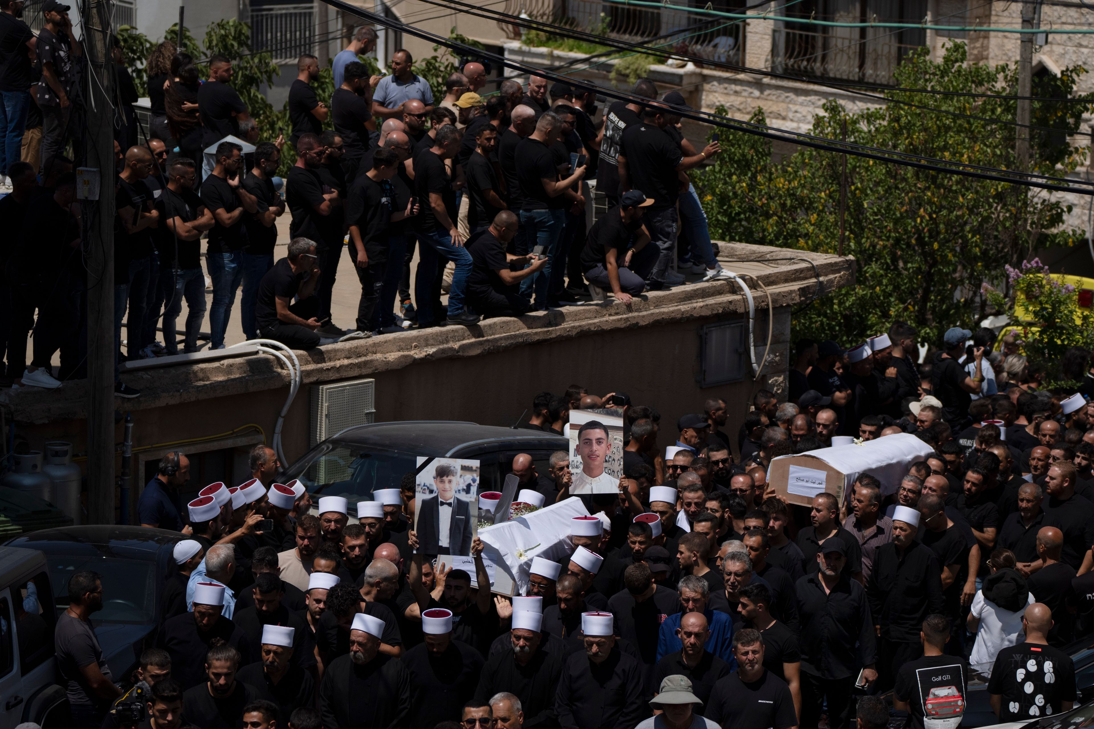 Mourners from the Druze minority carry the coffins of some of the 12 children and teens killed in a rocket strike at a soccer field during their funeral, in the village of Majdal Shams, in the Israeli-annexed Golan Heights, Sunday, July 28, 2024. It's the deadliest strike on an Israeli target along the country's northern border since the fighting between Israel and the Lebanese militant group Hezbollah began. (AP Photo/Leo Correa)