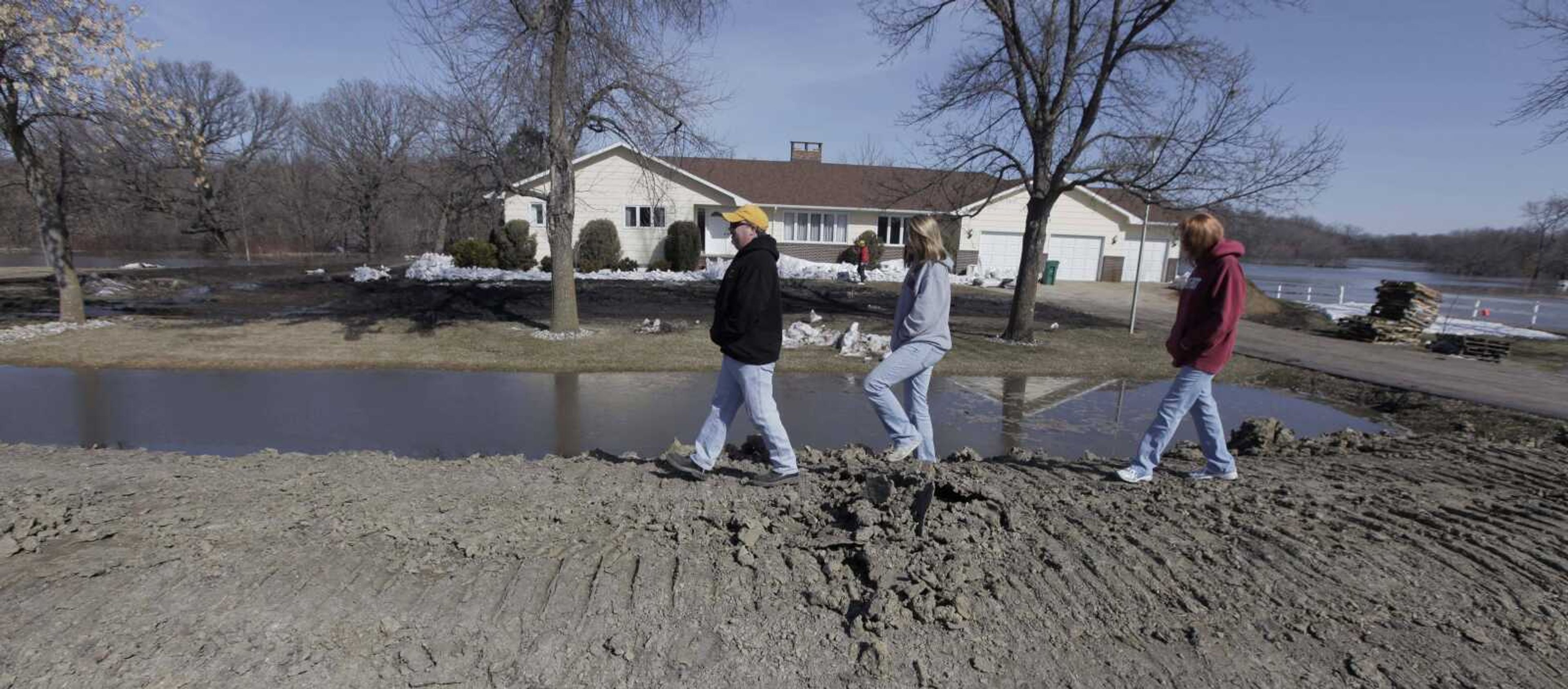 Clint Holowell, left, his daughter Catlyn and wife Cathy, right, go for a walk along an earthen levee in their neighborhood Sunday in Fargo, N.D. As residents in the area await the official crest of the Red River, well below 2010's record flood, communities along the river think they have avoided a repeat of last year's destruction. (M. Spencer Green ~ Associated Press)