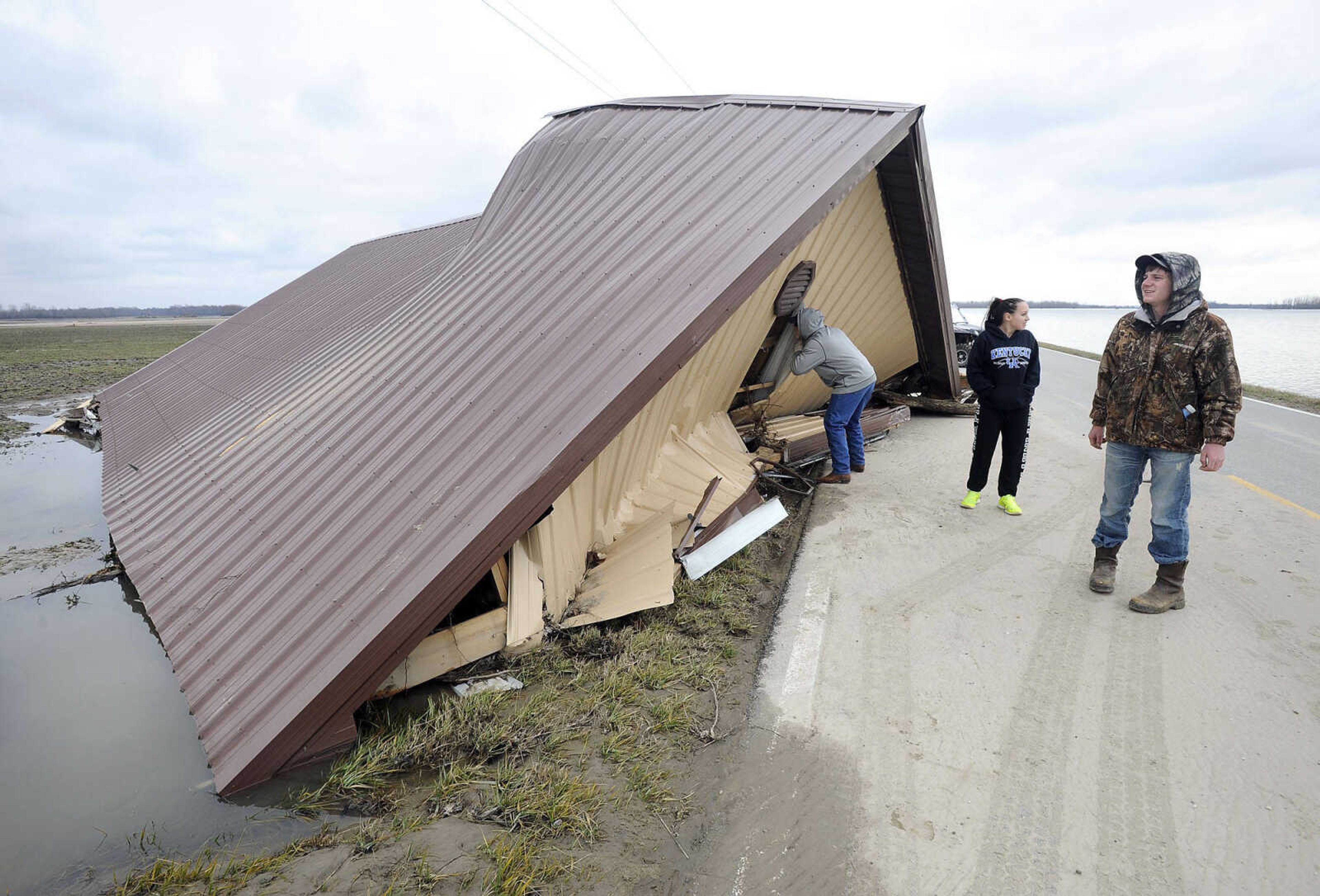 FRED LYNCH ~ flynch@semissourian.com
Ashlyn Brown, center, along with Wade Pecord, right, and Randy Brown, view on Saturday, Jan. 16, 2016 the farm shed that floated away from her house off Miller City Road two weeks ago. Floodwaters had receded enough to permit traffic on the road which is within sight of the Len Small levee that was breached on Jan. 2 by the rising river.