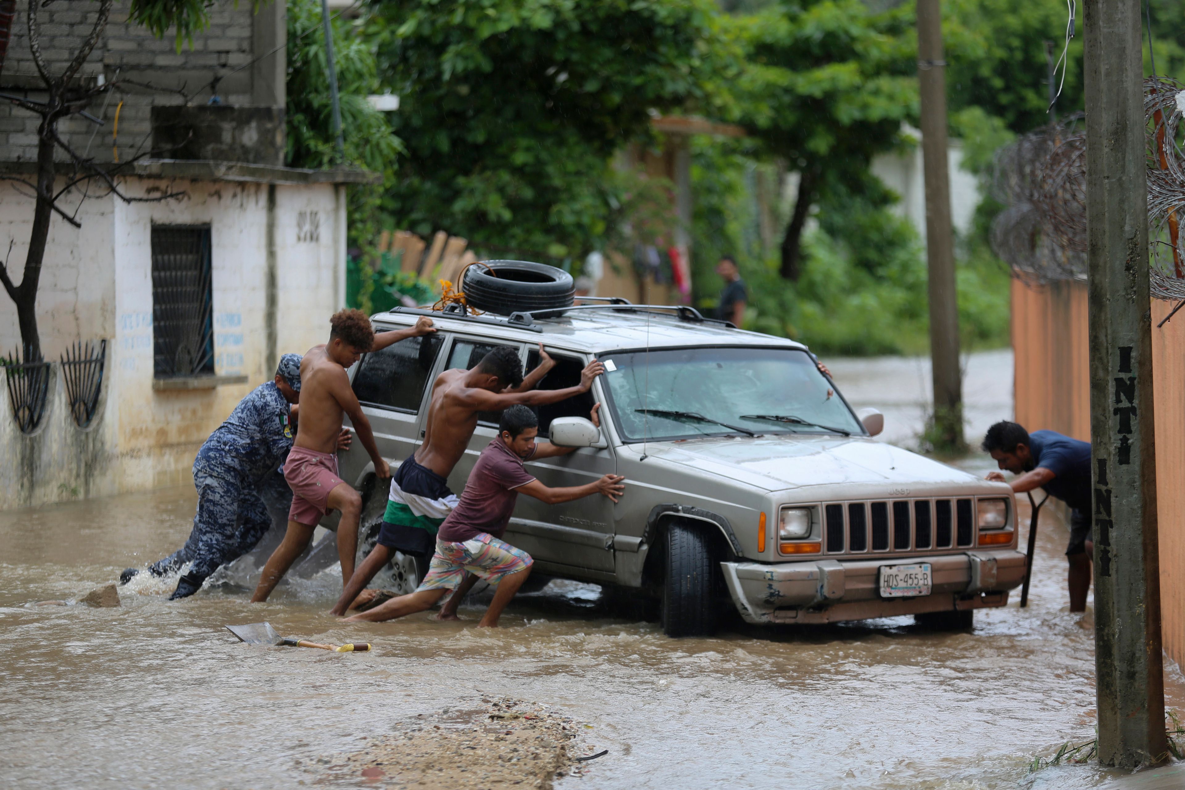 Residents work together to push a vehicle stuck on a street flooded by the passing of Hurricane John, in Acapulco, Mexico, Friday, Sept. 27, 2024. (AP Photo/Bernardino Hernandez)