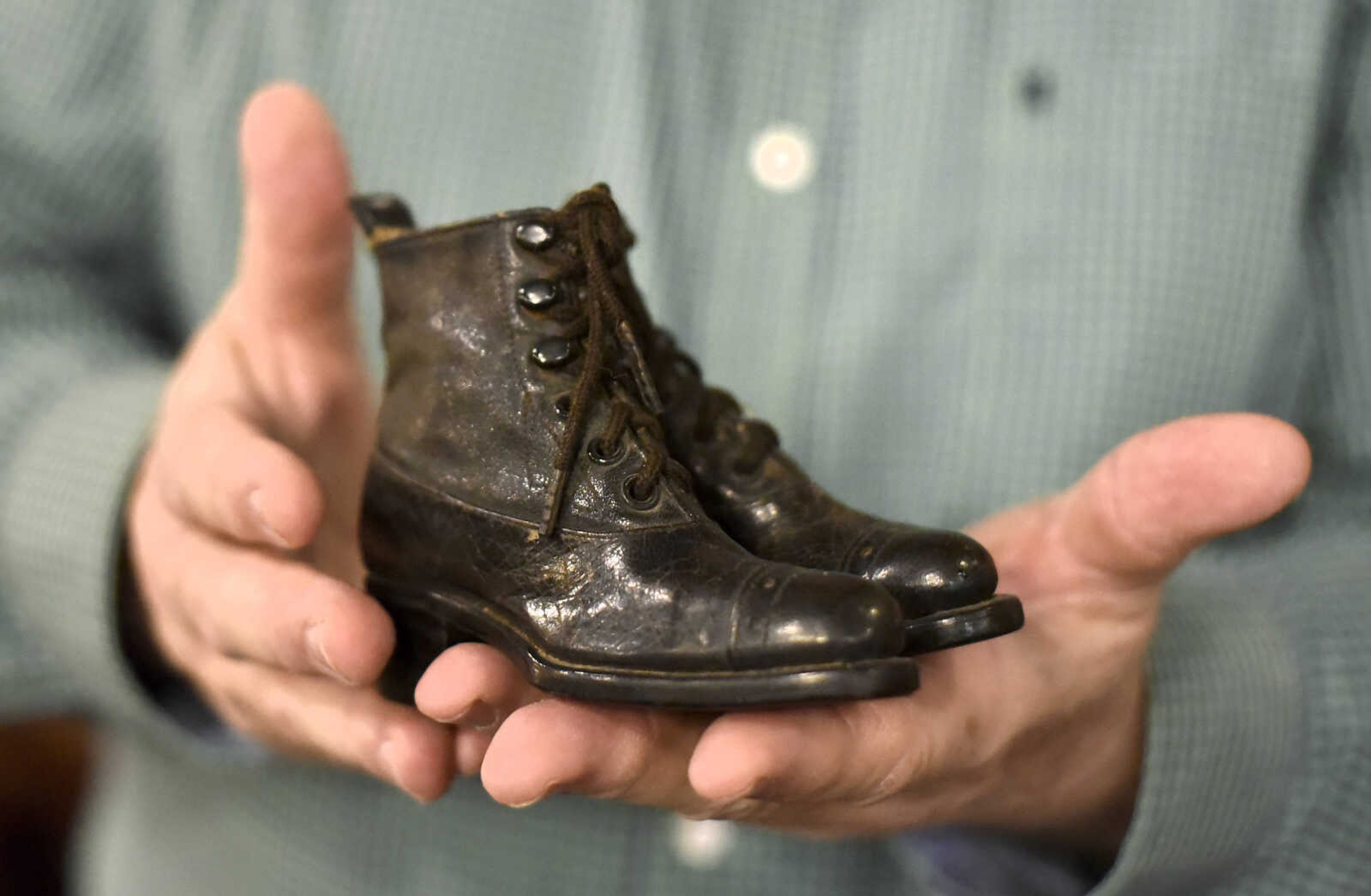 Harlan Smothers holds a pair of sample children's shoes inside his Fat Chance General Store in Cape Girardeau County.