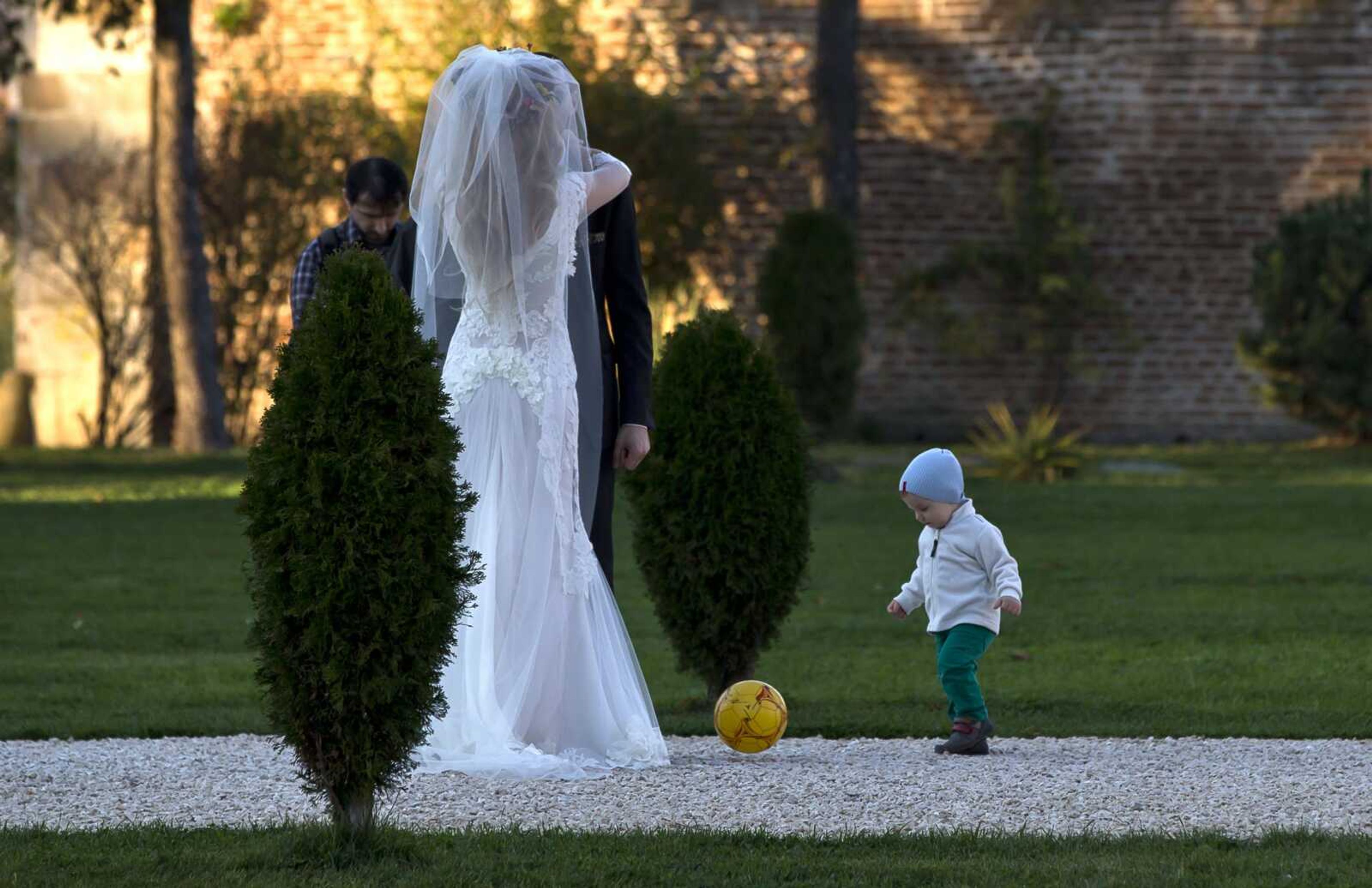 A child plays with a ball next to a couple posing for a photographer in a park Nov. 9, 2013, outside Bucharest, Romania, as temperatures reached an unseasonably warm 68 degrees. A new study says global warming is going to steal some of those exceedingly pleasant weather days from our future.