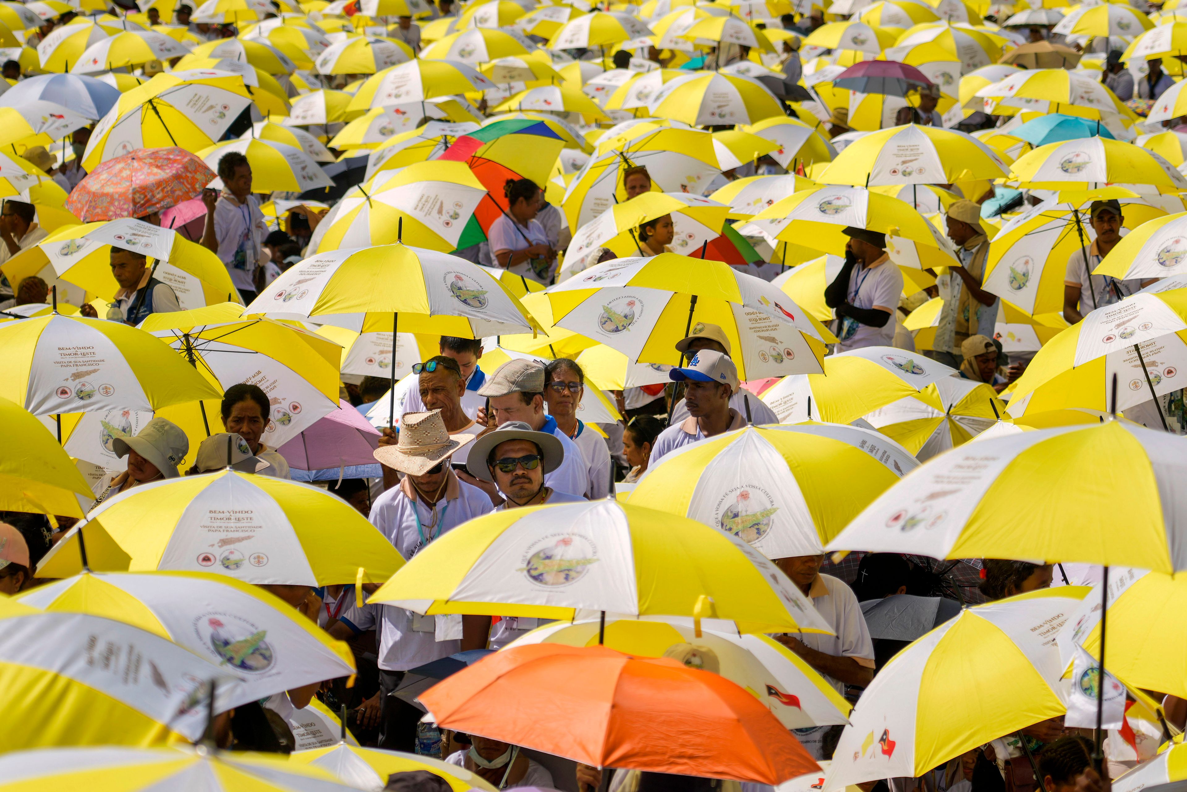 Faithful use umbrellas with the colors of the Vatican flag to shield themselves from the sun as they wait for a mass presided over by Pope Francis to start in Tasitolu, some 8 kilometers west of Dili, East Timor, Tuesday, Sept. 10, 2024. (AP Photo/Gregorio Borgia)