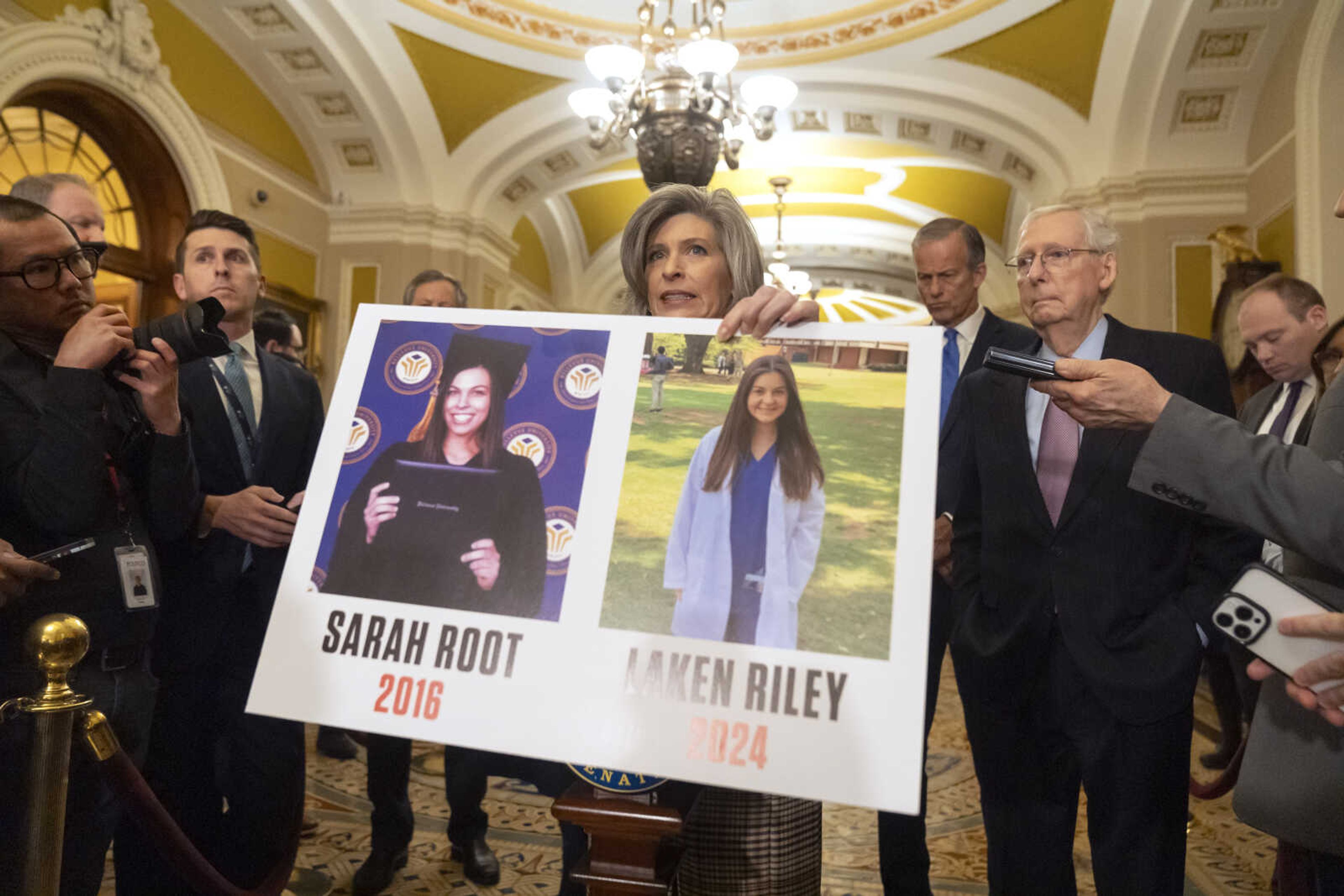 FILE - Sen. Joni Ernst, R-Iowa, holds a poster with photos of murder victims Sarah Root and Laken Riley as she speaks on Capitol Hill, Feb. 27, 2024, in Washington. House Republicans have passed a bill that would require federal authorities to detain unauthorized immigrants who have been accused of theft, seizing on the recent death of Laken, a nursing student in Georgia. The bill sends a rebuke to President Joe Biden's border policies just hours ahead of his State of the Union address. However, the nine-page bill had little chance of being taken up in the Democratic-controlled Senate. (AP Photo/Mark Schiefelbein, File)