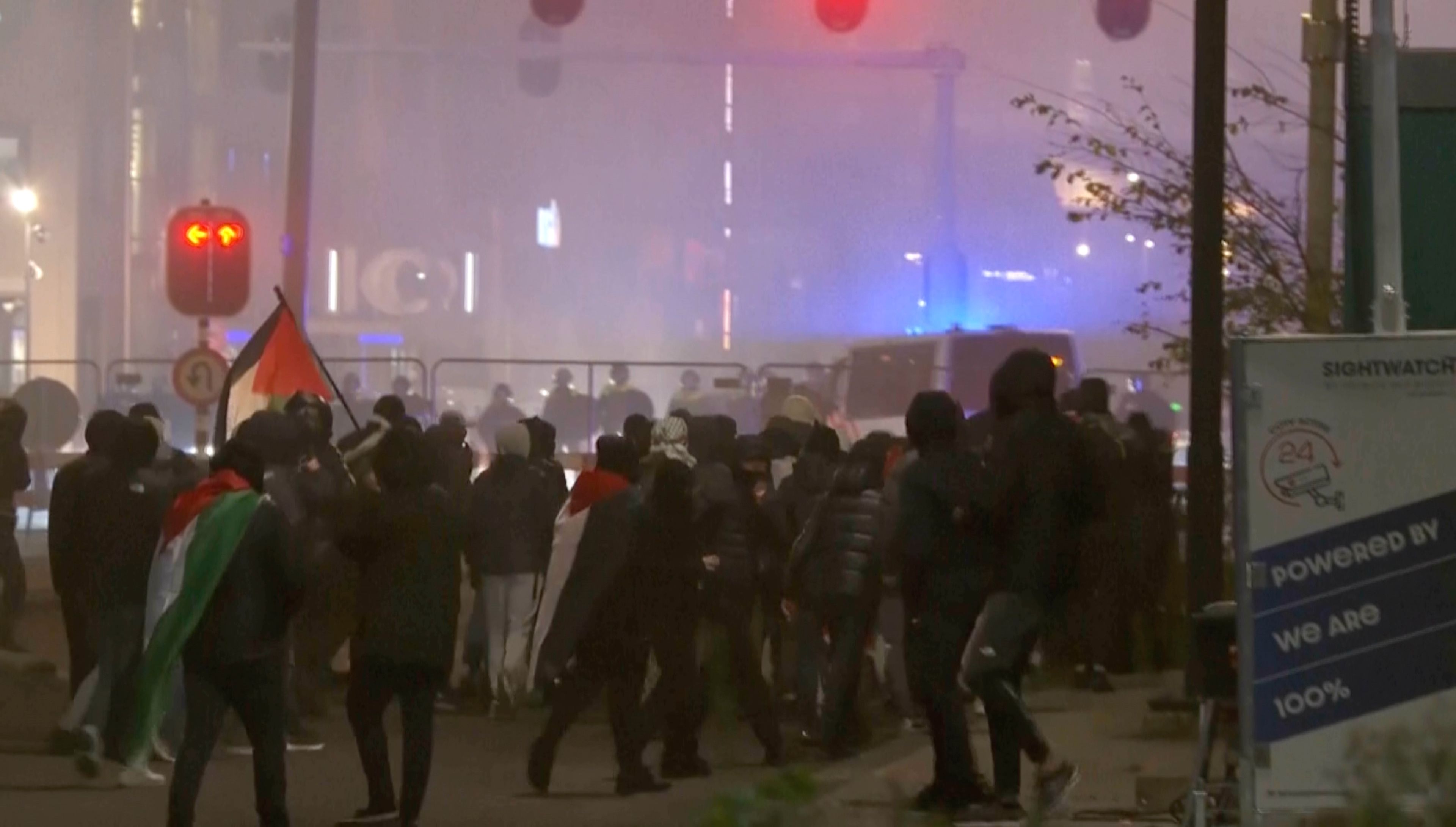 In this image taken from video, a group of pro-Palestinian protesters walk toward police line, with police vans driving in the background, near the soccer stadium in Amsterdam, Netherlands, Thursday, Nov. 7, 2024. (RTL Nieuws via AP)