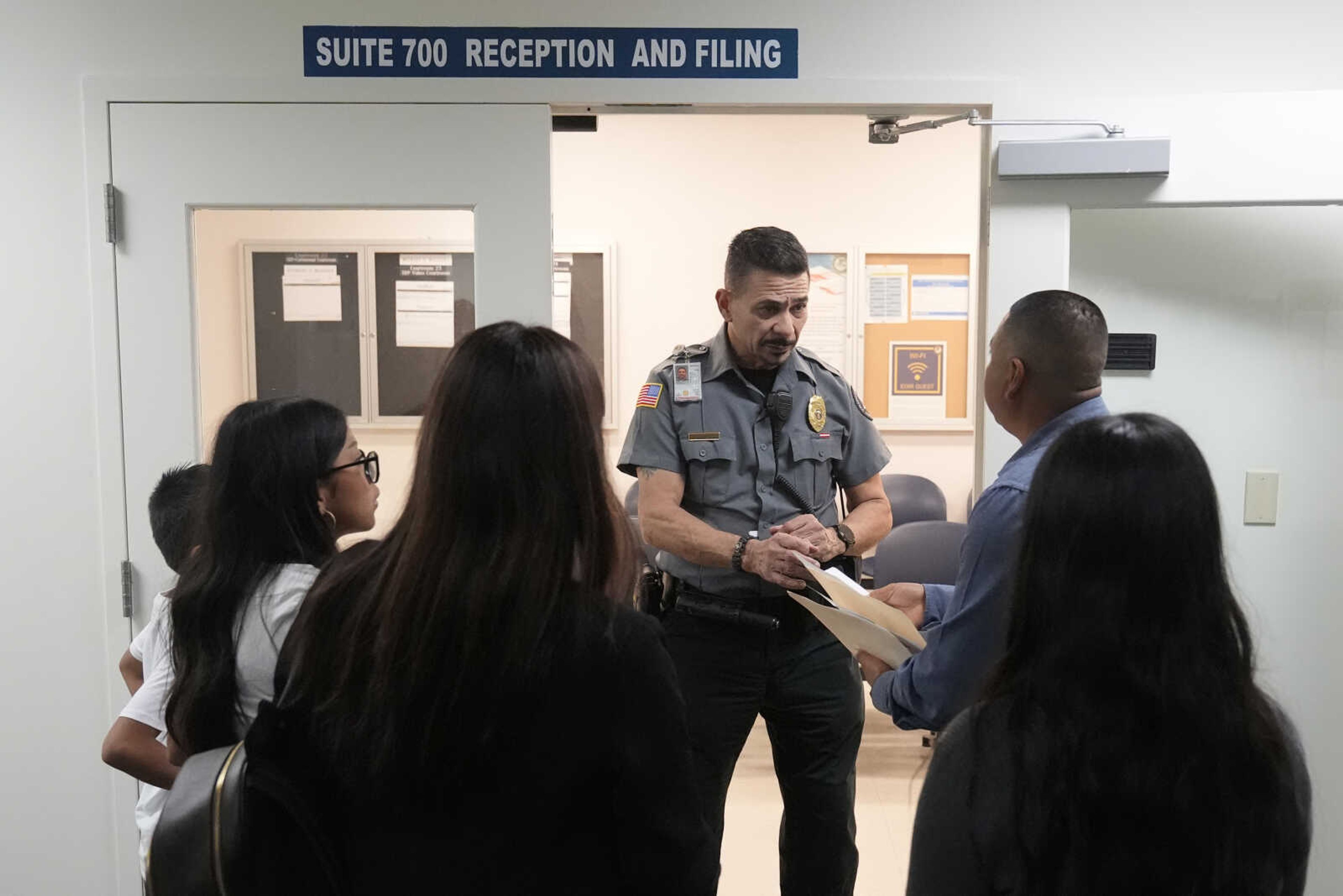 An officer listens to a question as he directs people to a courtroom Jan. 10 in an immigration court in Miami. Immigration courts are buckling under an unprecedented 3 million pending cases, most of them newly arrived asylum-seekers. The number of migrants trying to fight their deportation in front of a U.S. judge has grown by 50% in less than a year.