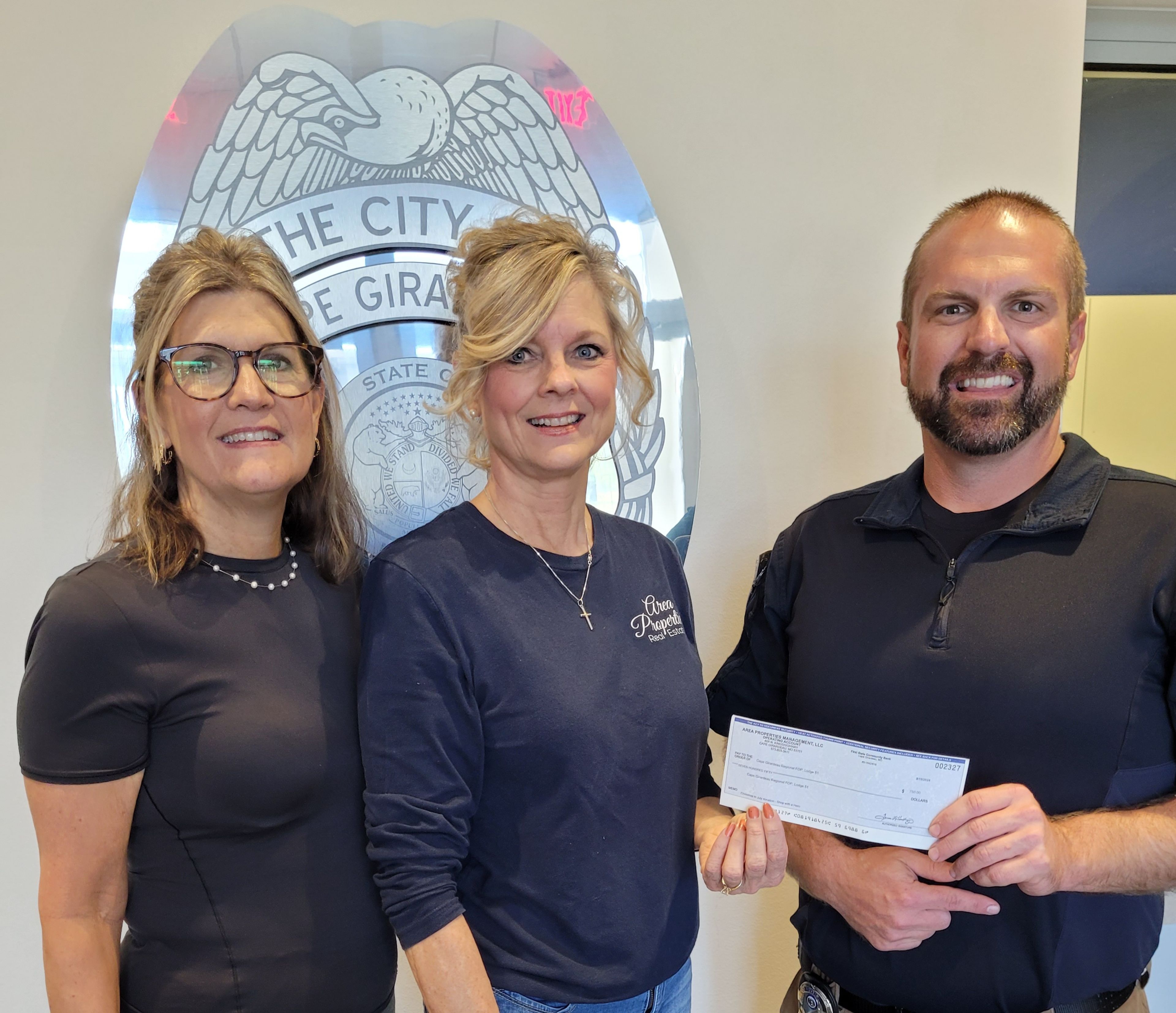 Becky Harding and Lori Fowler of Area Properties present a check for $750 to Cpl. Johnny Spencer of the Cape Girardeau Fraternal Order of Police, Lodge 51,  to help needy children shop during the annual Shop with a Hero event at the Cape Walmart Supercenter in December.