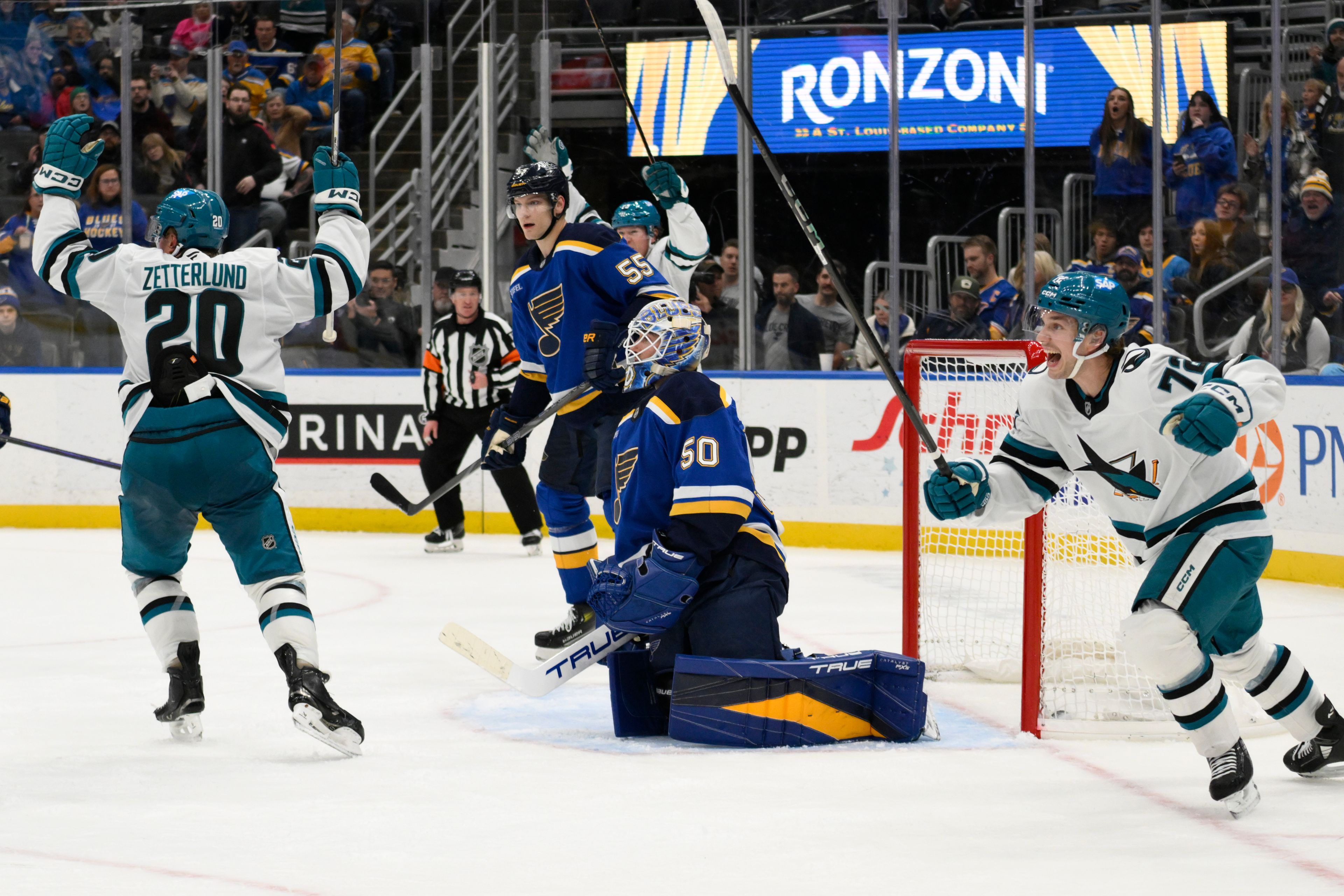 St. Louis Blues defenseman Colton Parayko (55) and goaltender Jordan Binnington (50) look on as San Jose Sharks left wing Fabian Zetterlund, far left, and left wing William Eklund, far right, react to a goal from center Alexander Wennberg, not pictured, during the third period of an NHL hockey game Thursday, Nov. 21, 2024, in St. Louis. (AP Photo/Jeff Le)