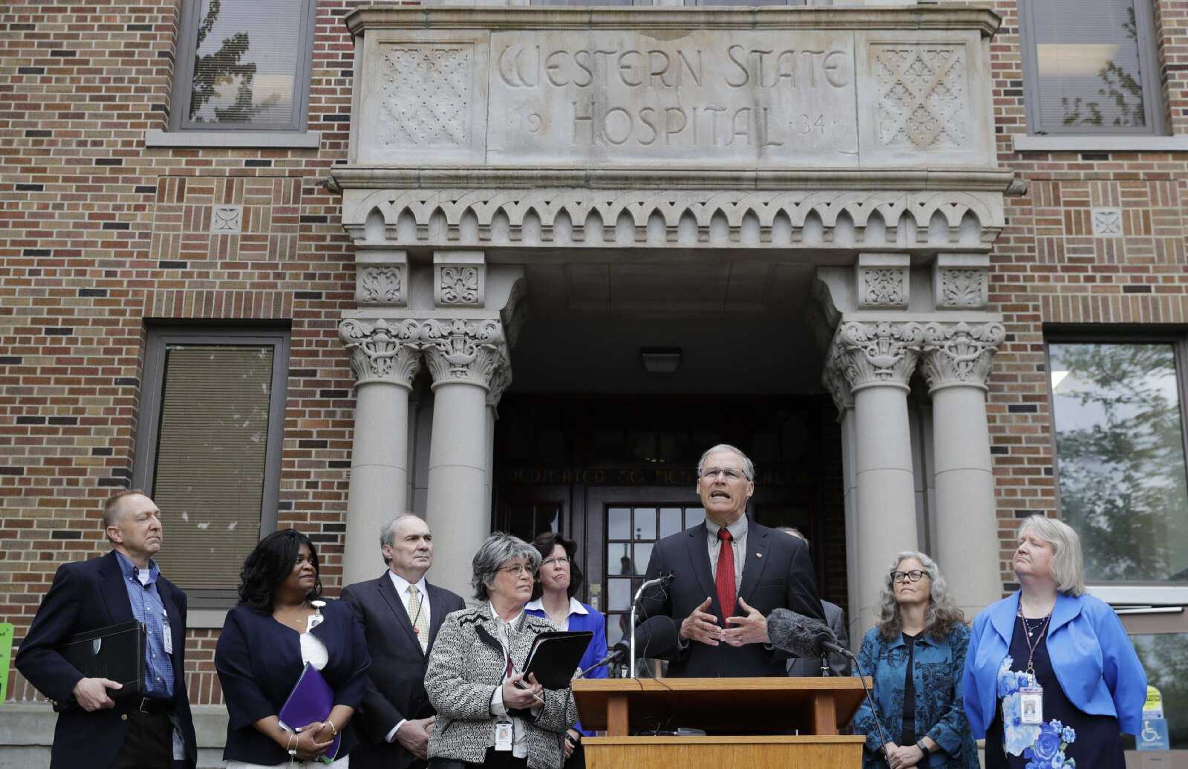 Washington Gov. Jay Inslee, third from right, speaks in front of Western State Hospital in Lakewood, Washington. Hundreds of employees at Washington state's largest psychiatric hospital have suffered serious injuries during assaults by patients, resulting in millions of dollars in medical costs and thousands of missed days of work.