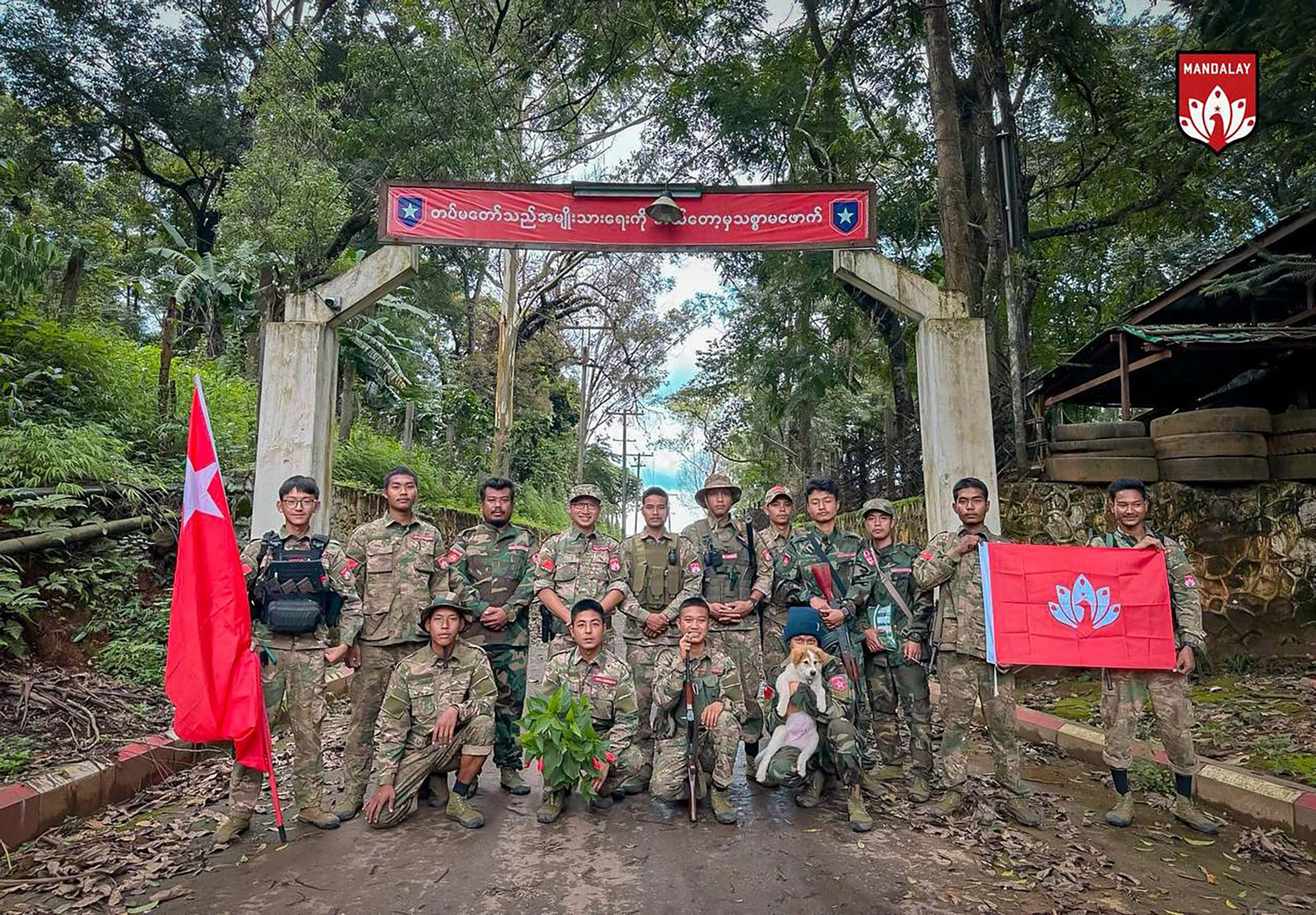 In this photo provided by Mandalay People's Defence Force, its members pose for a photograph in front of the gate of the captured army battalion in Mogok township in Mandalay region, Myanmar, on July 25, 2024. (Mandalay People's Defence Force via AP)