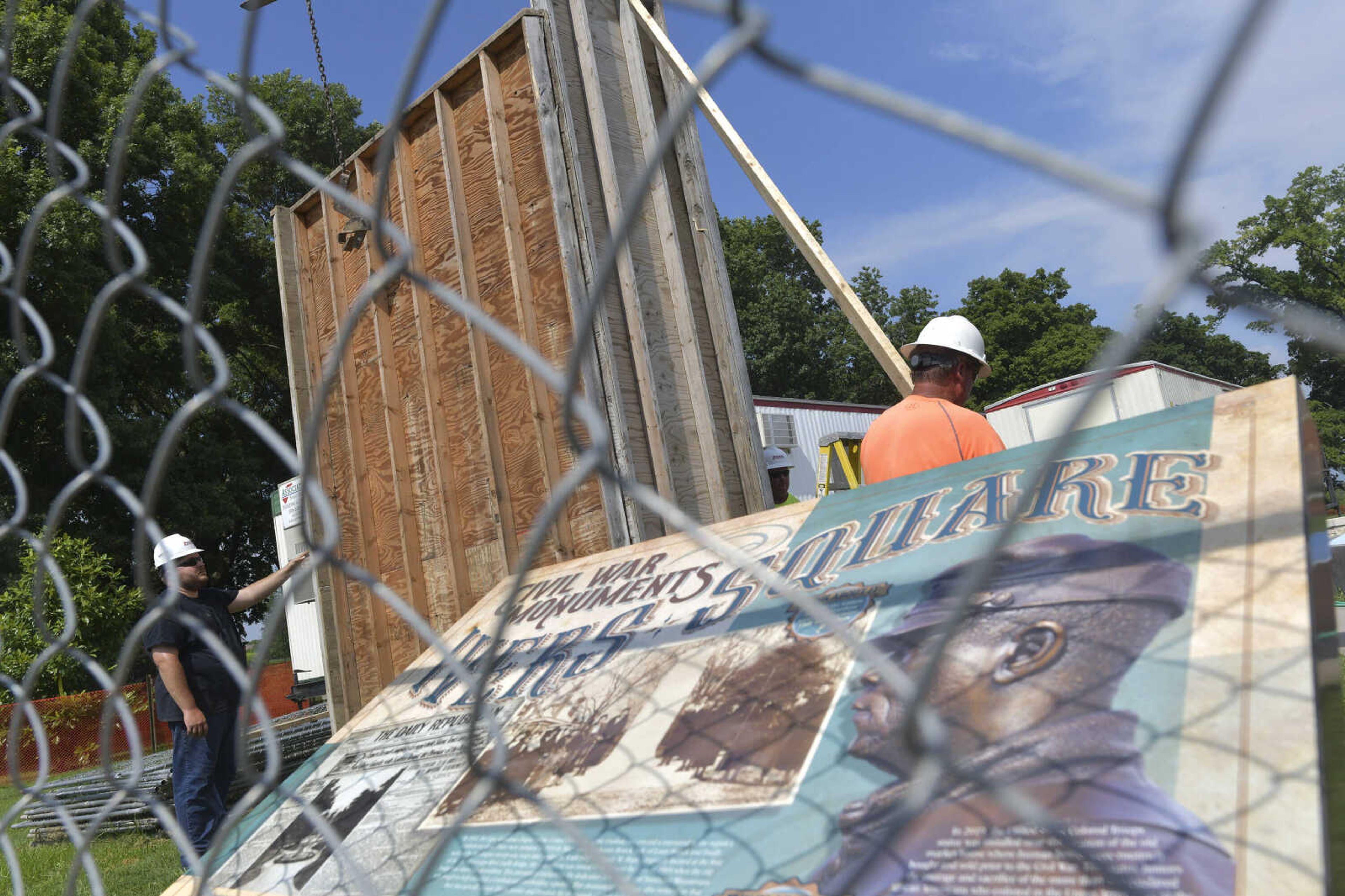 A placard detailing historical information about the various Civil War monuments in Ivers Square is seen through a fence as construction workers erect a wooden box around a Confederate States of America monument Tuesday, July 7, 2020, in Cape Girardeau.