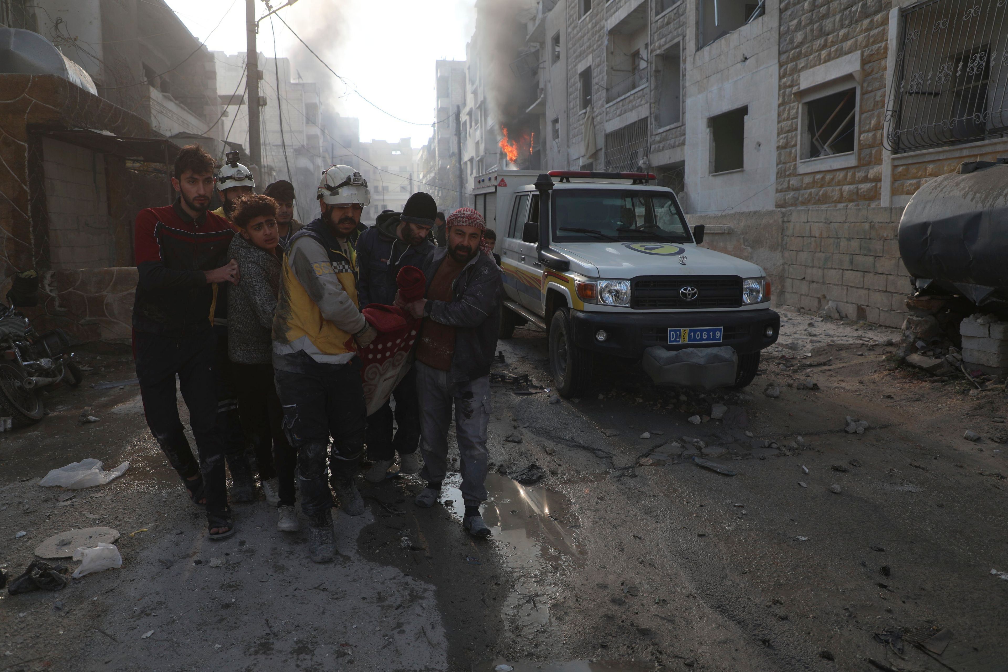 This photo provided by the Syrian Civil Defence White Helmets, which has been authenticated based on its contents and other AP reporting, shows a Syrian White Helmet civil defence worker and civilians carry a victim after the Syrian government forces hit Idlib city, Syria, Monday, Dec. 2, 2024. (Syrian Civil Defence White Helmets via AP)